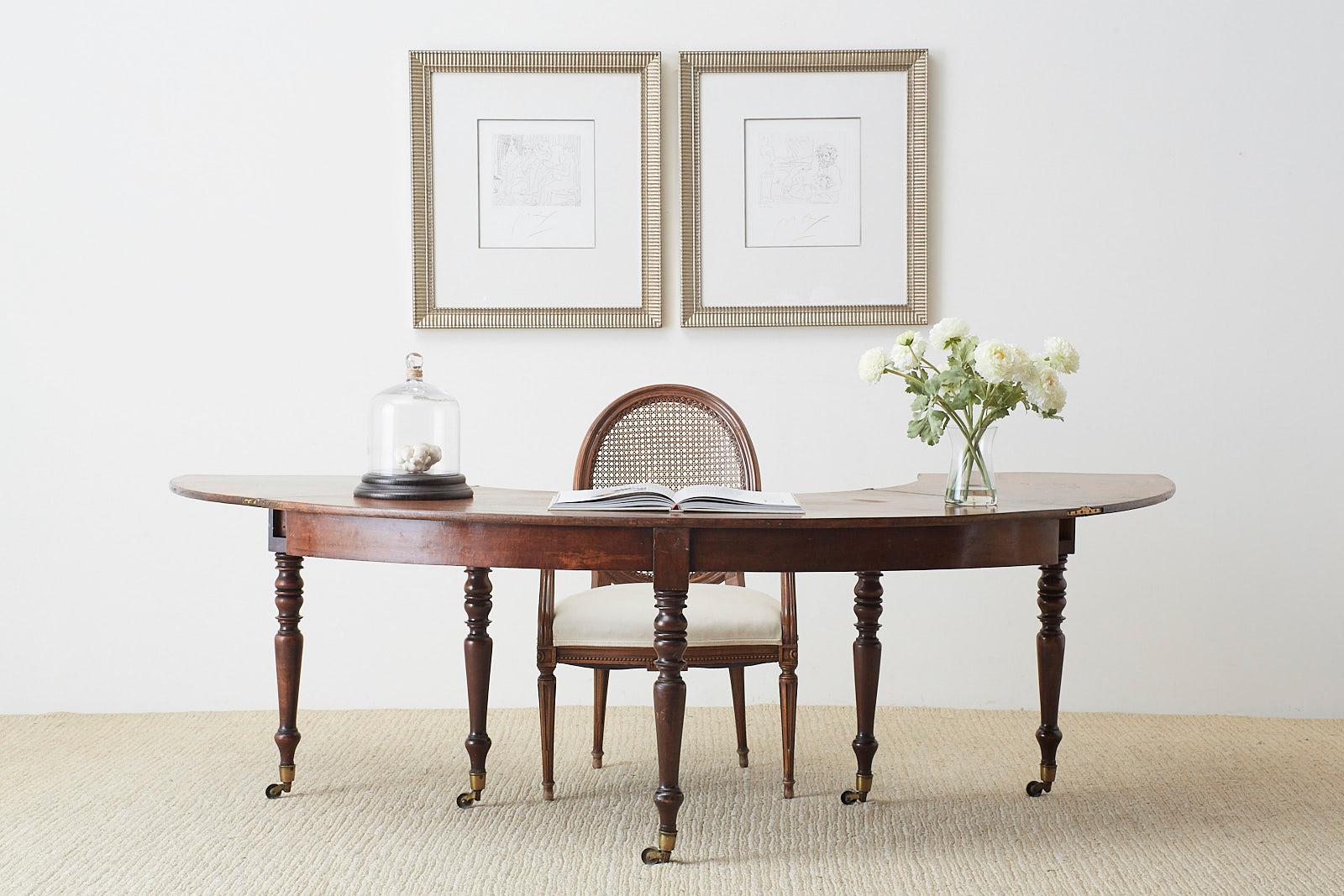 Rare late George III Regency period hunt table, serving table or wine tasting drop leaf table constructed from rich mahogany. Features a gate leg flip top that extends the table into a semicircle or demilune form. Measures 70 inches wide and 30