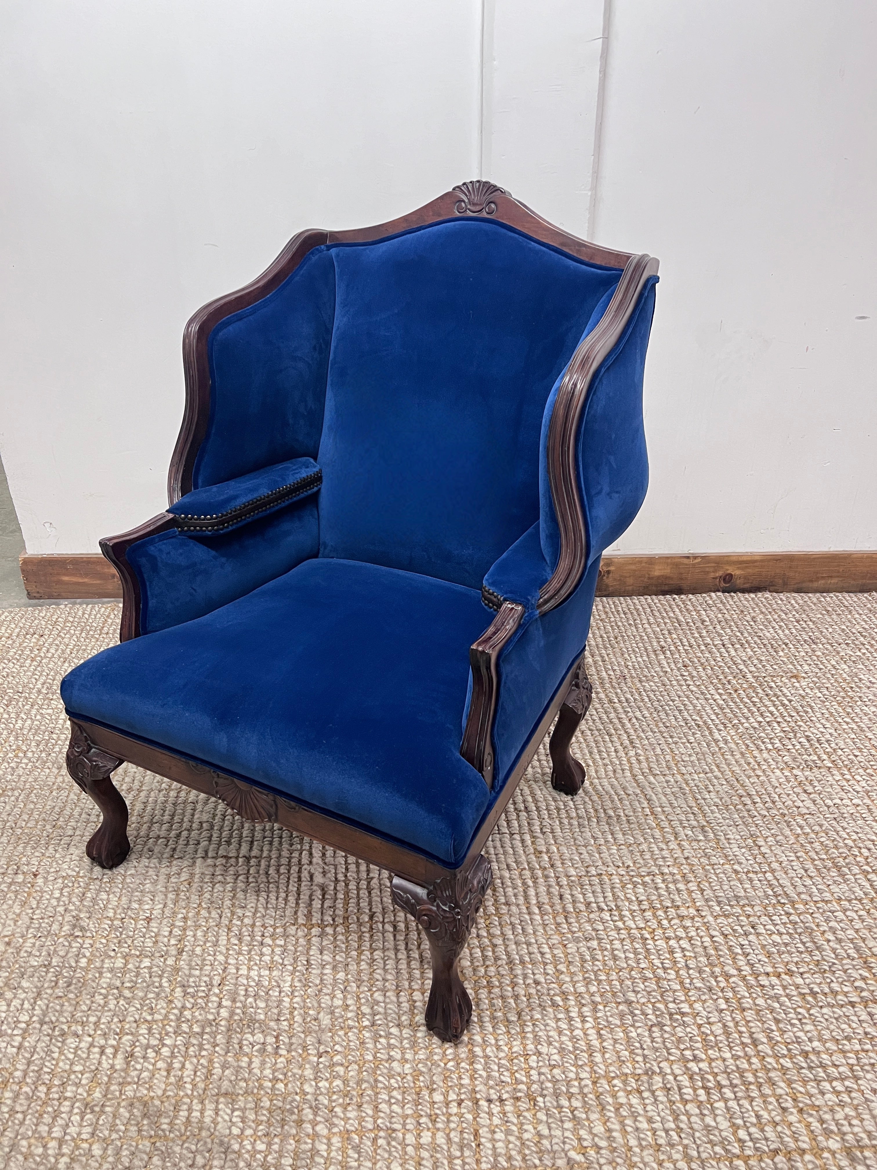 Ein außergewöhnlicher Wingback Chair mit großen geschwungenen Flügeln und Armlehnen im Inneren des mit Bronze-Nagelköpfen verzierten Rahmens.  Der Stuhl ist im französischen Barock-Regence-Stil gehalten, obwohl es sich um einen Stuhl des frühen 20.