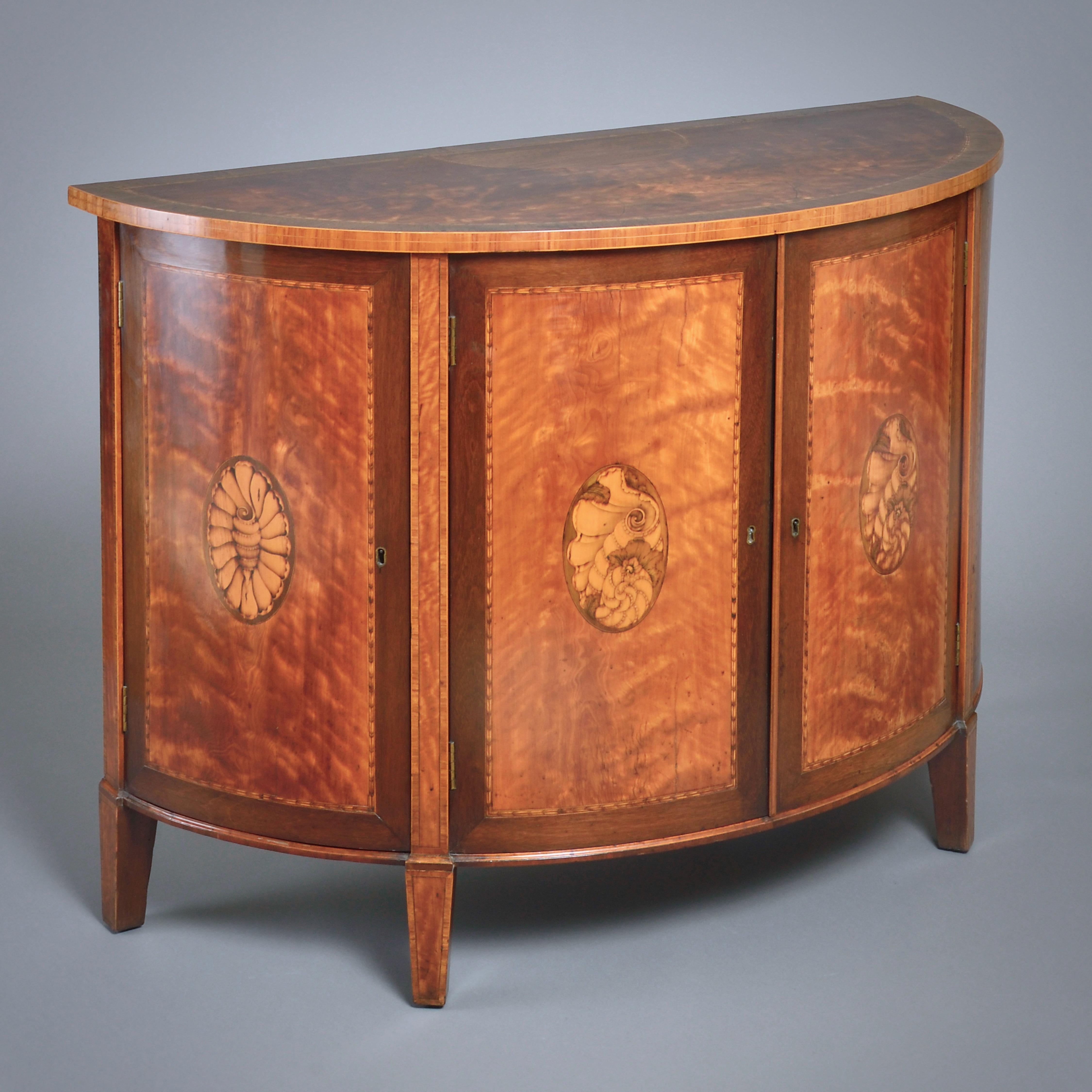 A FINE GEORGE III SATINWOOD, AMARANTH AND MARQUETRY COMMODE BY GILLOWS, CIRCA 1790.

Each of the four doors inlaid with a conch shell.

In 1788, Gillows supplied a satinwood and amaranth commode to John Christian for Workington Hall, Cumbria. This