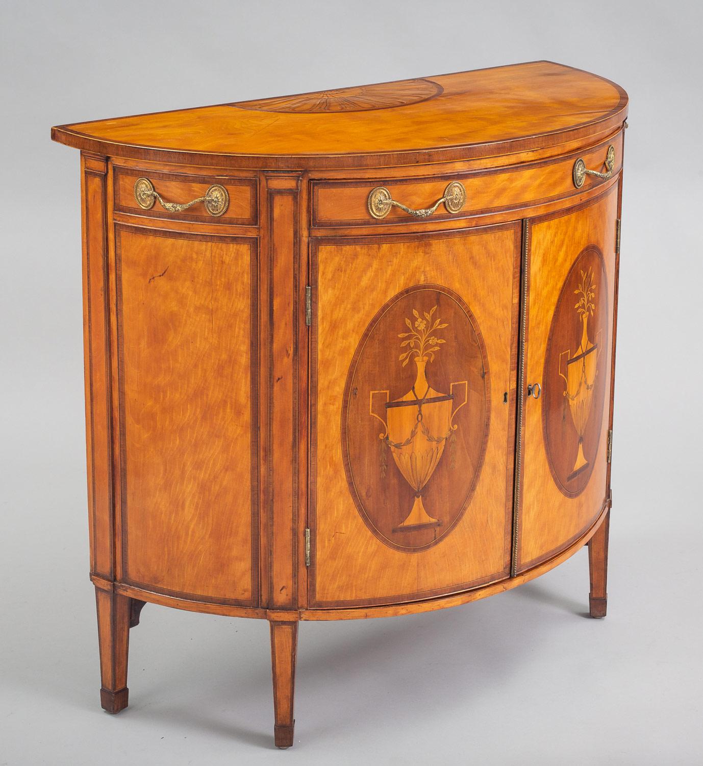 Fine George III satinwood demilune console cabinet inlaid with marquetry, crossbanded with mahogany, decorated with inlays of Grecian urns on the double doors, the top inlaid with shell and fan paterae, the single drawer with gilded handles and the