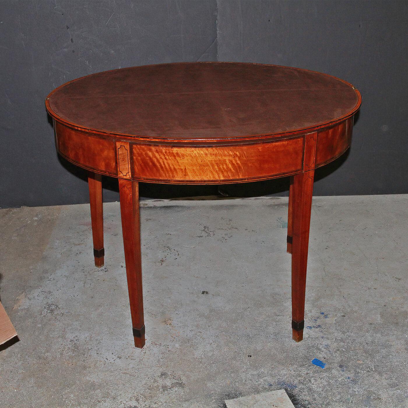 A fine George III satinwood banded demilune card table or game table with a baize lined interior, ebony line inlays, and rosewood crossbanding, with square tapering double swing legs. Ca 1780.

Dimensions: 38.25