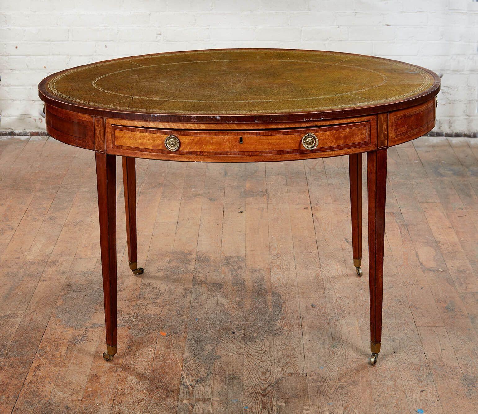 Very fine Georgian Satinwood oval writing/library table, the inset leather top with rosewood banding, over four drawers with original gilt lacquered brass pulls and standing on square tapered legs ending in original brass box casters.