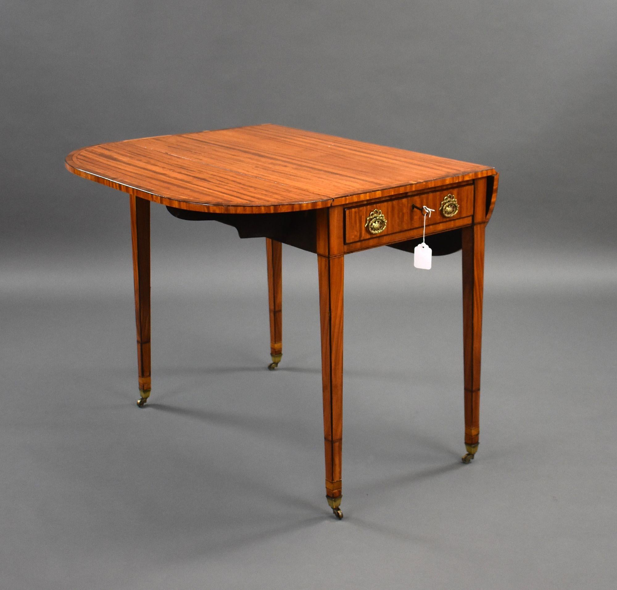 For sale is a good quality George III Satinwood pembroke table, having a well figured top with two drop leaves, the central drawer with brass handles, and a faux drawer on the opposing side, standing on elegant tapered legs terminating on castors,