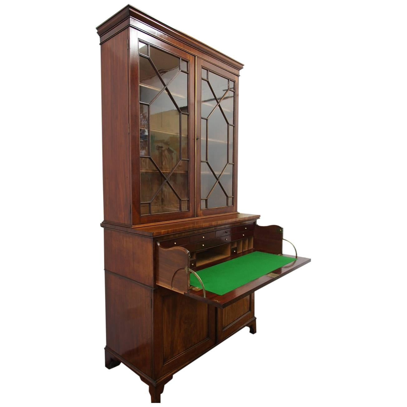 George III secretaire bookcase in figured Spanish mahogany, circa 1820. The upper section has classical astragal glazing with three adjustable shelves and fluted mahogany fronting; all surmounted by a simple figured mahogany frieze and neat