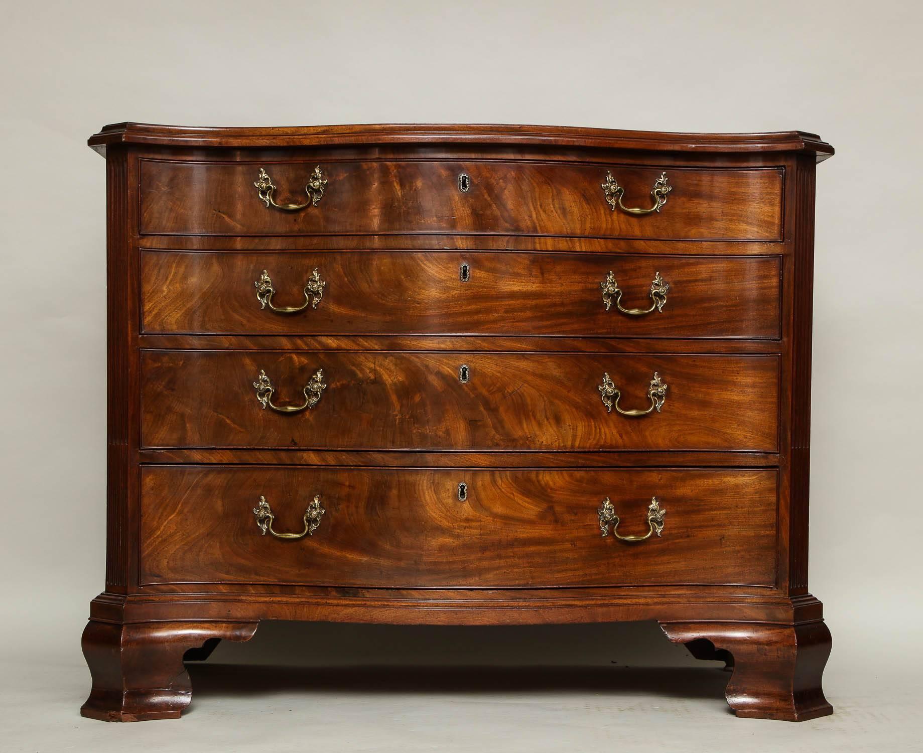 Very fine Georgian mahogany serpentine chest of drawers having a richly molded top over serpentine front, the canted edges featuring pilaster uprights with stop fluted molding, the graduated drawer fronts with original Rococo brass pulls retaining