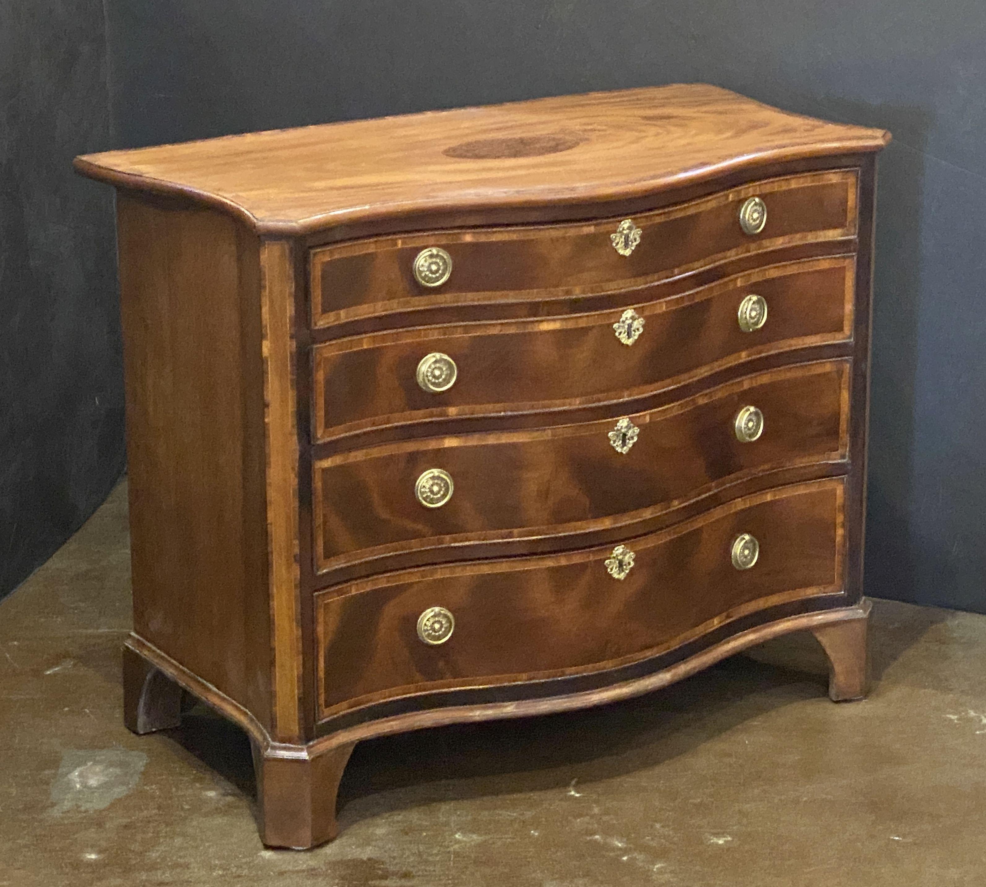Un'elegante cassettiera d'epoca di George III con fronte a serpentina in mogano e legno di raso, un segno distintivo del design dei mobili inglesi del XVIII secolo. 

Realizzata nel periodo georgiano, intorno al 1780, la cassapanca incarna
