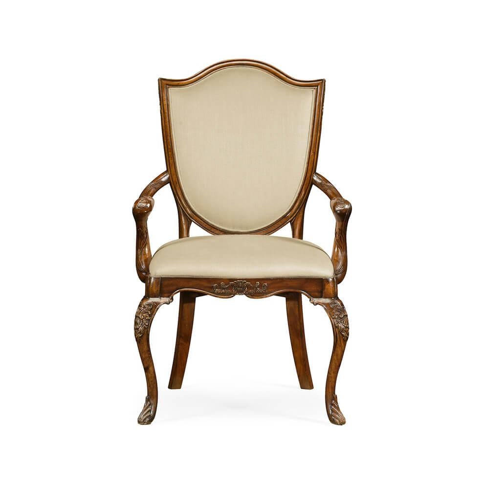 Classic Hepplewhite style mahogany armchair with an upholstered shield back and seat, the slender cabriole legs and seat rail with shallow carved Rococo details of shells and leaves. The foot is enhanced with a finely carved sabot. After an original