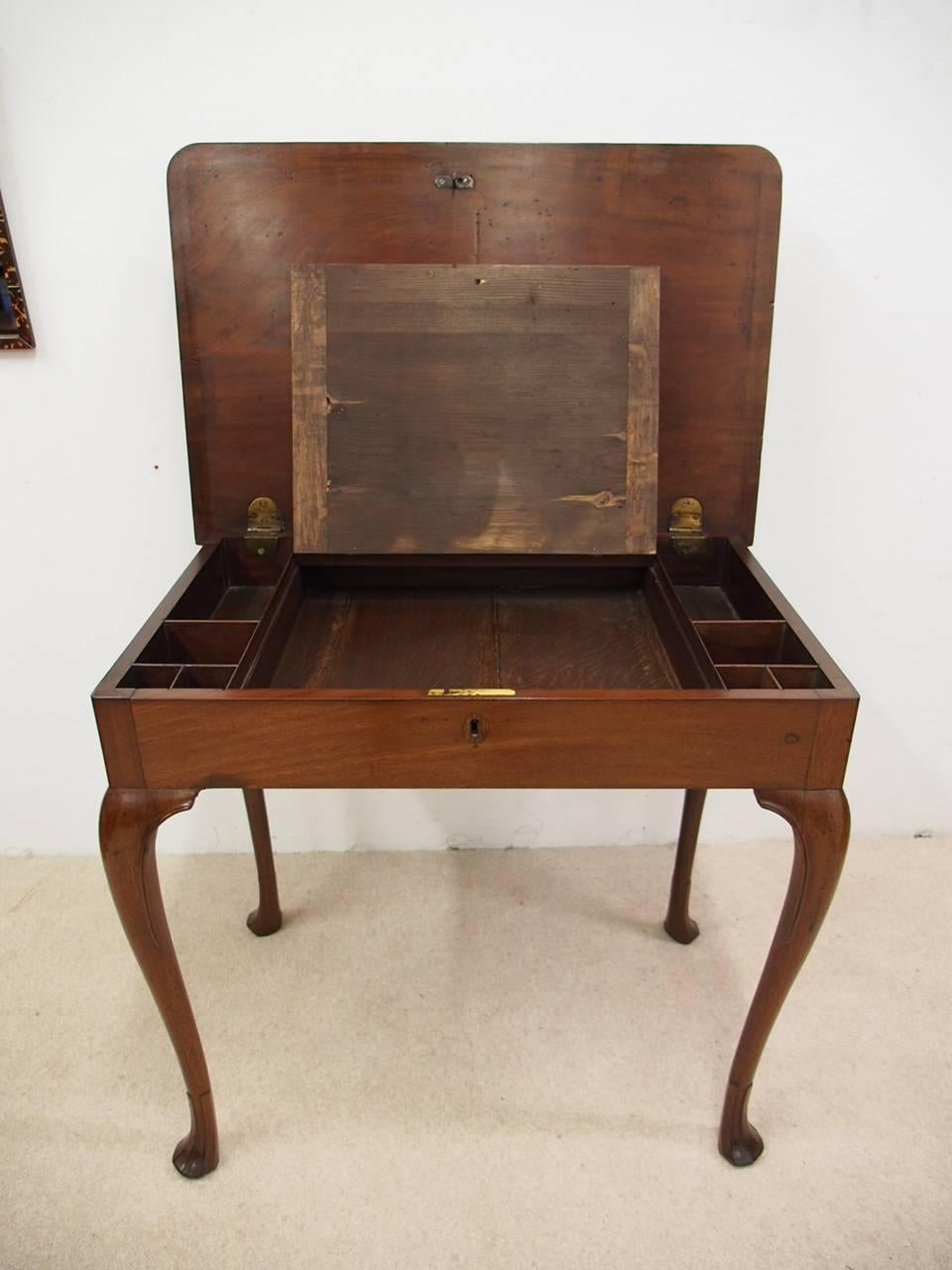 George III side/writing table in figured Spanish mahogany, circa 1770. With rounded corners and moulded edges to the rectangular top, it lifts up to reveal a fitted interior and leather covered writing slide. It is all sitting on cabriole supports