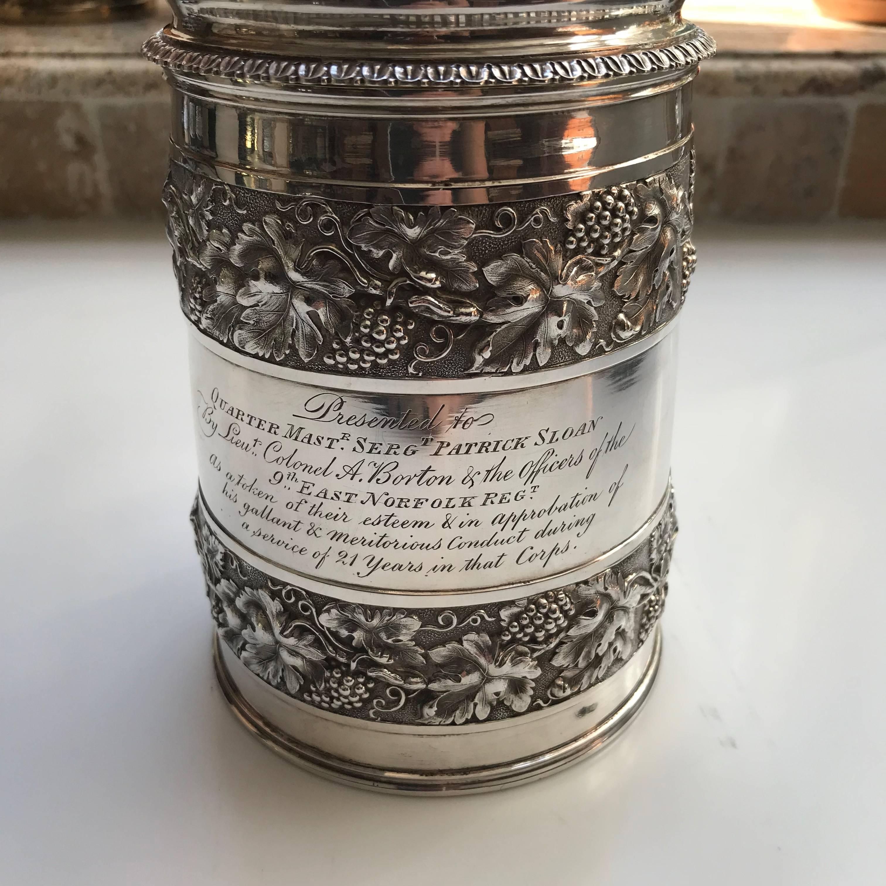 A George III silver and silver-gilt tankard, Rebecca Emes & Edward Barnard, London 1814, the cover with pine cone finial and shell thumbpiece, the tapering body with two bands of fruiting vine decoration, inscribed 'Presented to Quarter Mast'r