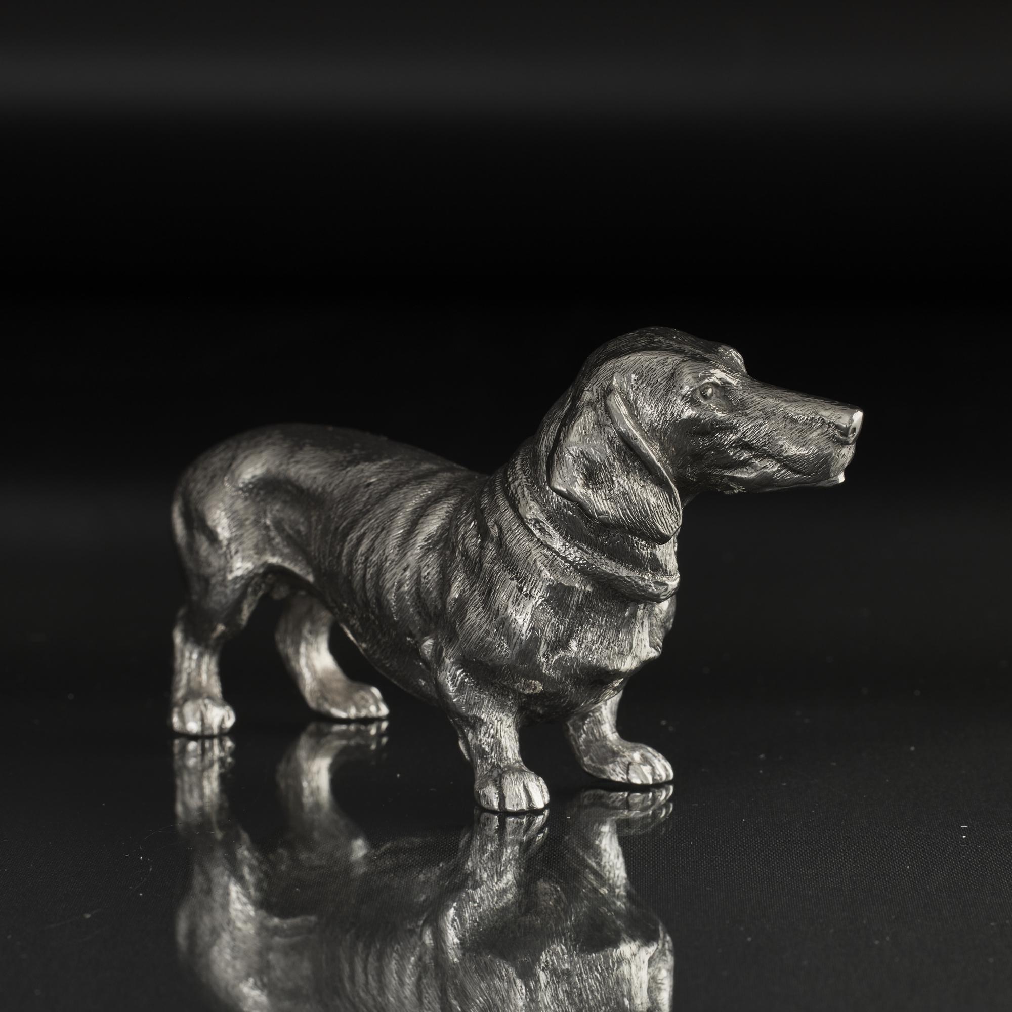 An excellent modern rendition of a smooth-haired dachshund - or sausage dog as we used to call them - in solid cast and hand chased silver. The familiar definition, detailing and proportions of this popular dog are all very good.
 
 The name