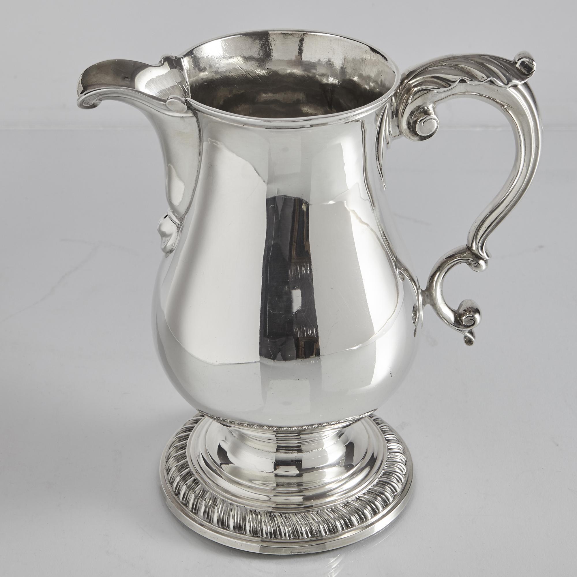 In excellent and original condition, this is a Classic, heavy-gauge antique George III silver beer jug in a design that personifies the style of the period at the end of the 18th century. Of baluster form and with scroll and leaf mounts, the stepped