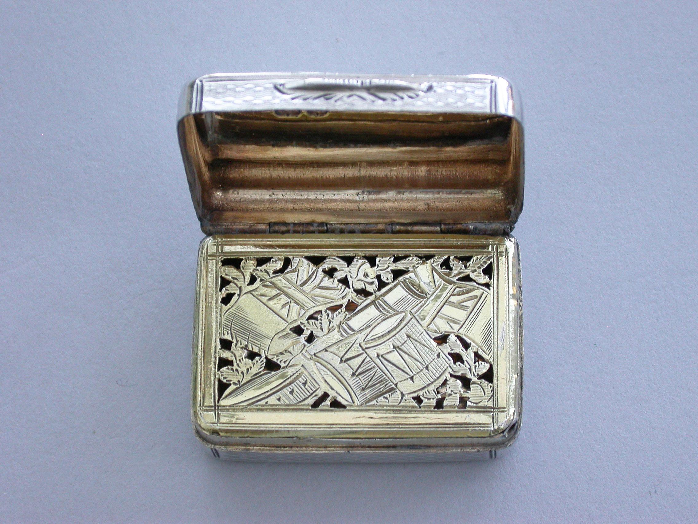 A rare George III silver Vinaigrette of rounded rectangular form with engine turned decoration, the cover with a circular monogrammed cartouche, the silver gilt interior with a finely pierced and engraved grille depicting various military