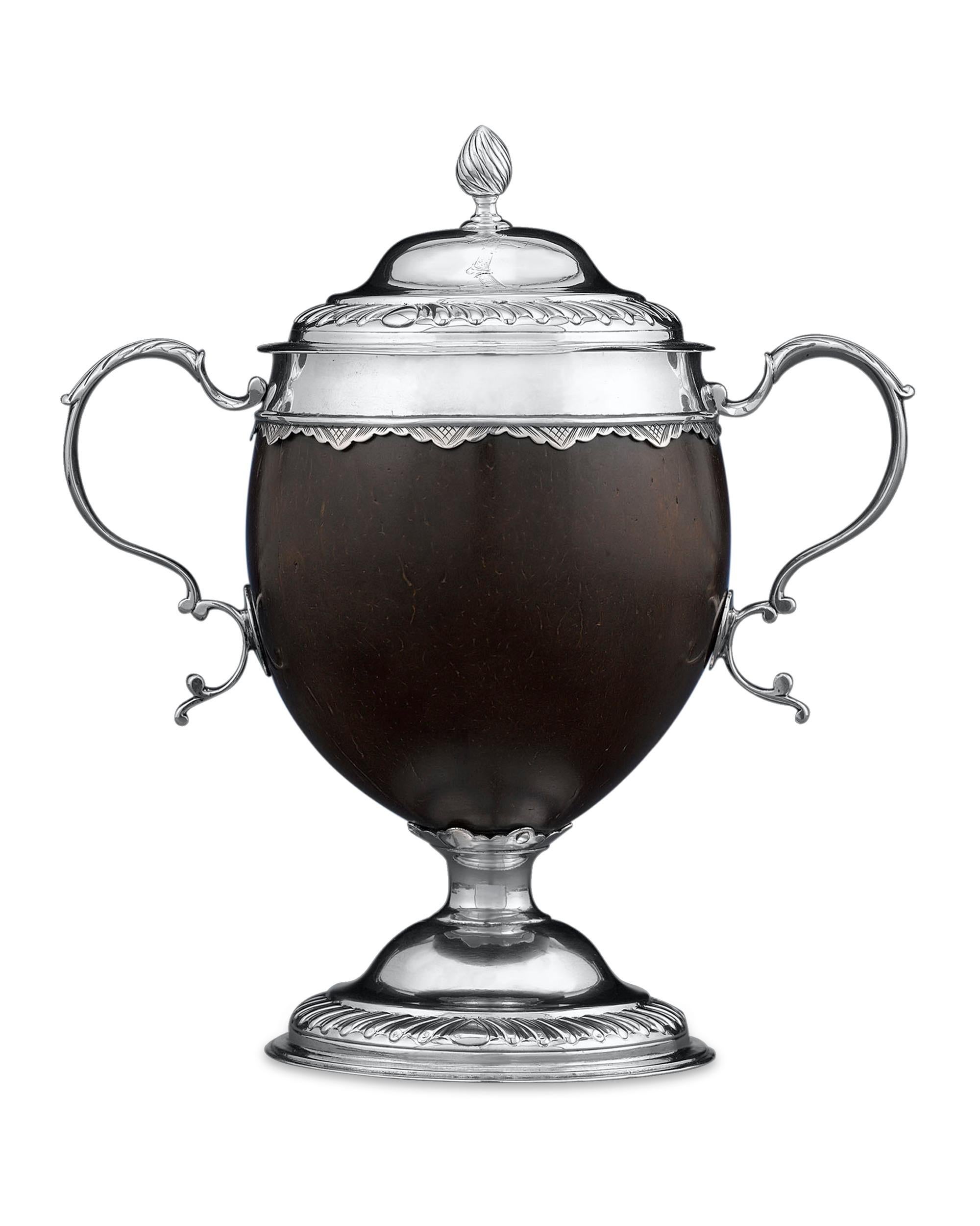 Exotic materials and classical design distinguish this rare, George III-period silver mounted coconut cup. Mounted sterling silver displaying classic Georgian decorative accents such as egg-and-dart borders, the polished shell is adorned with a