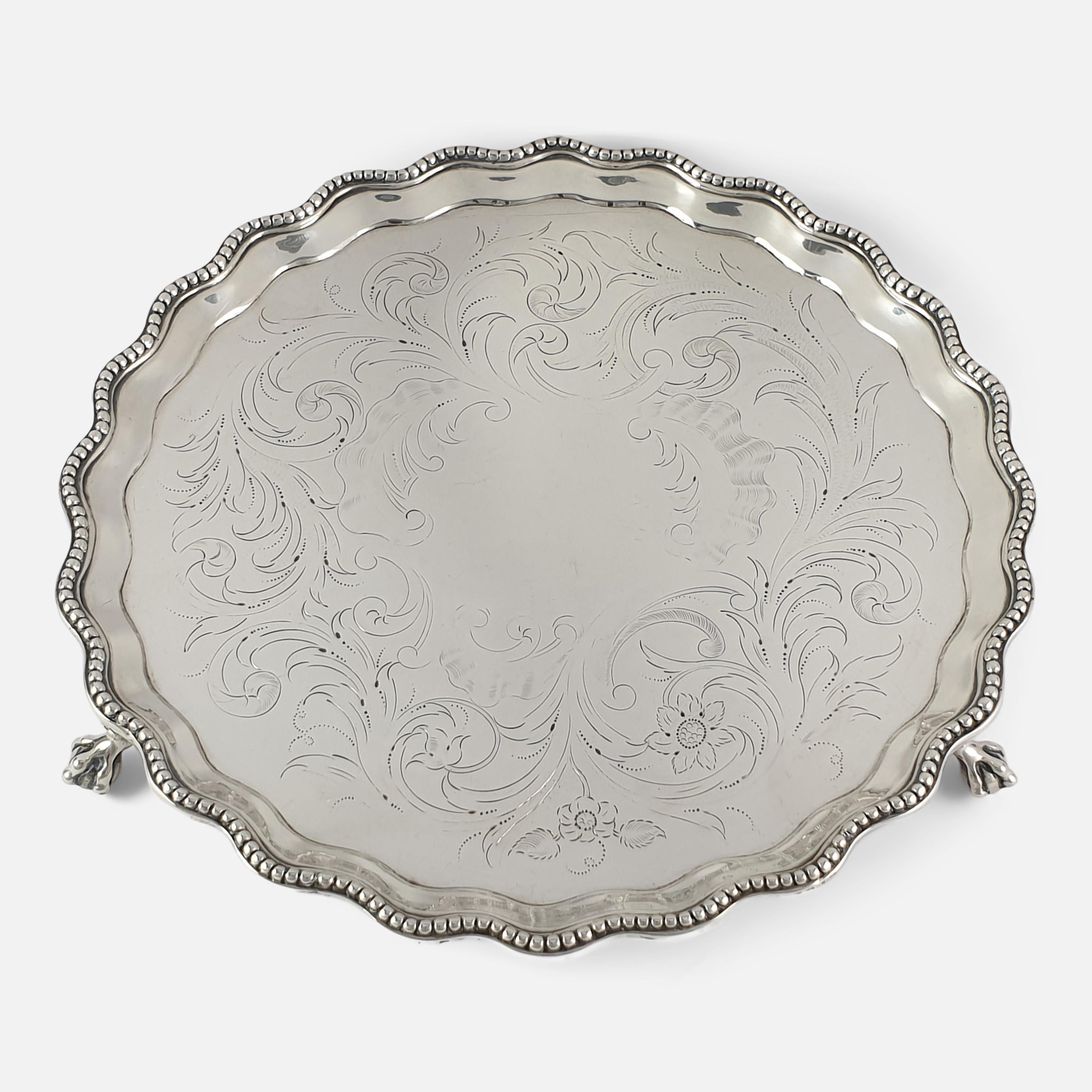 A George III sterling silver Salver by Hester Bateman, London, 1780. The Salver is of circular form, with a beaded border, sitting on three claw and ball feet. The center of the Salver has a later foliate scroll engraved decoration. The hallmarks