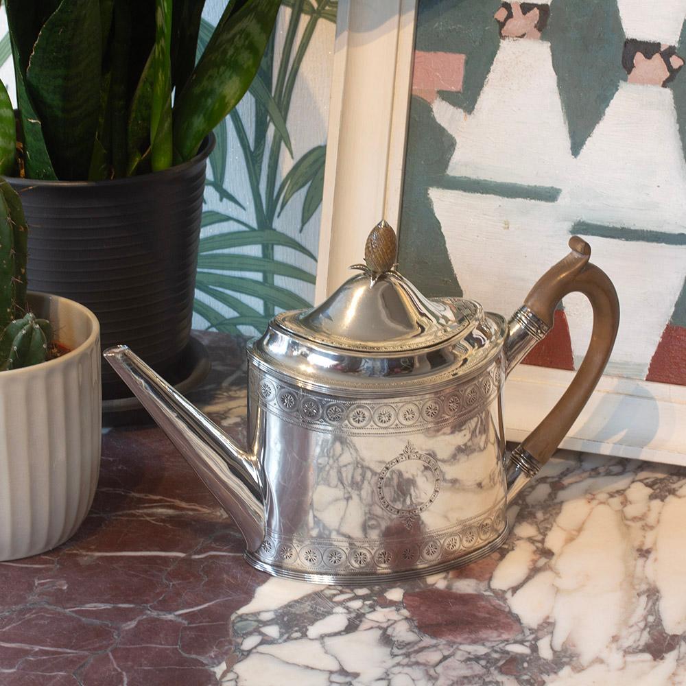 Punzierungen Datiert 1796

Wir freuen uns, Ihnen aus unserer Silbersammlung diese originale Teekanne aus George III Silber von Peter & Ann Bateman anbieten zu können. Die Teekanne in länglich-ovaler Form mit geradem, ansteigendem Ausguss und