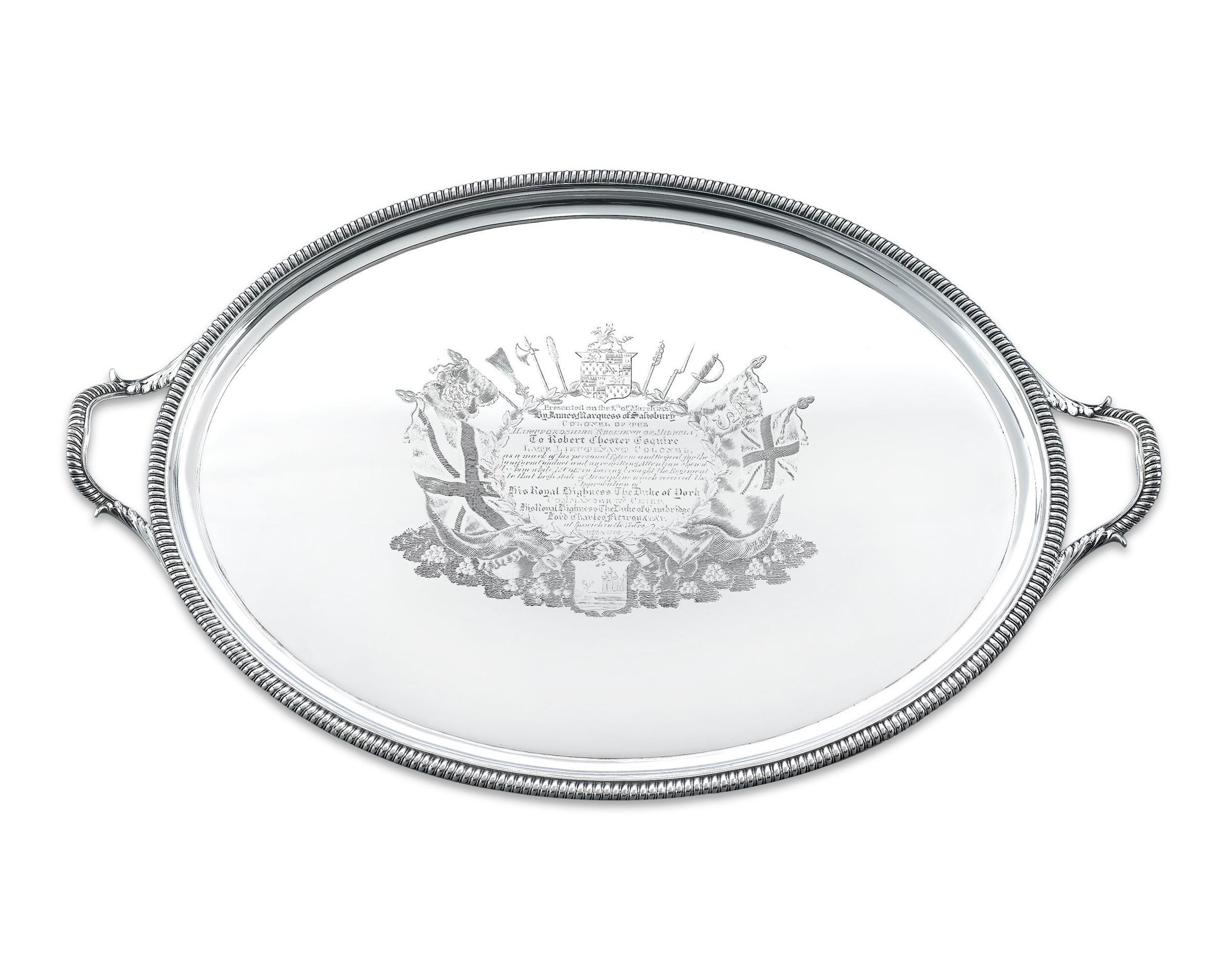 This fascinating George III silver tray is a work of skillful English artistry, intricately chased and engraved it represents a prestigious commemorative gift for service. The tray rests on 4 bracket feet with oval handles and a delightful gadrooned