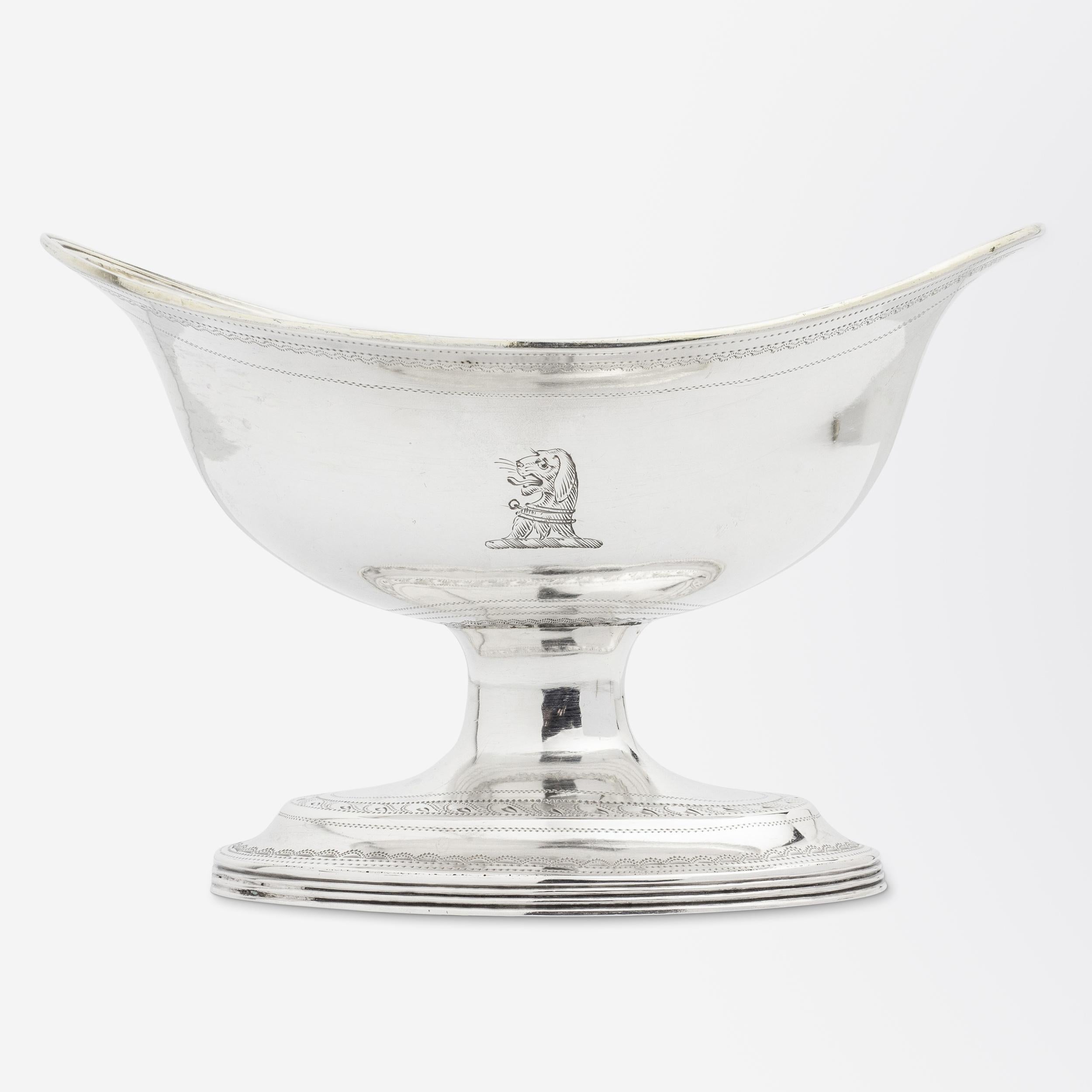 A George III period sterling silver salt cellar with a gilt wash interior and hand-chased details by two members of the famed English silversmithing family, Peter & Ann Bateman. An engraving to the front shows a dog's head crest and to the interior