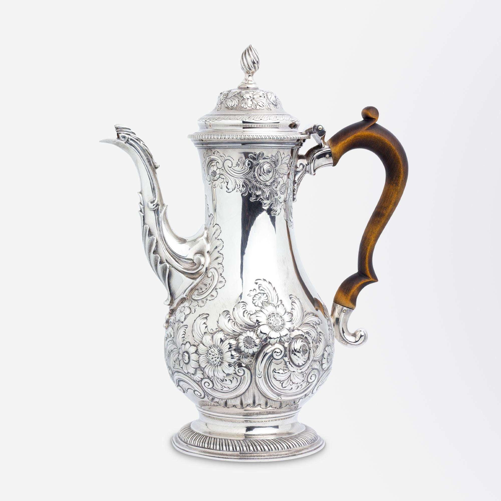 A George III sterling silver coffee pot with a wooden handle likely by Charles Wright of London. The pot features what could be described as Rococo period repousse swags and floral sprays which were often seen in art and design during the mid 18th