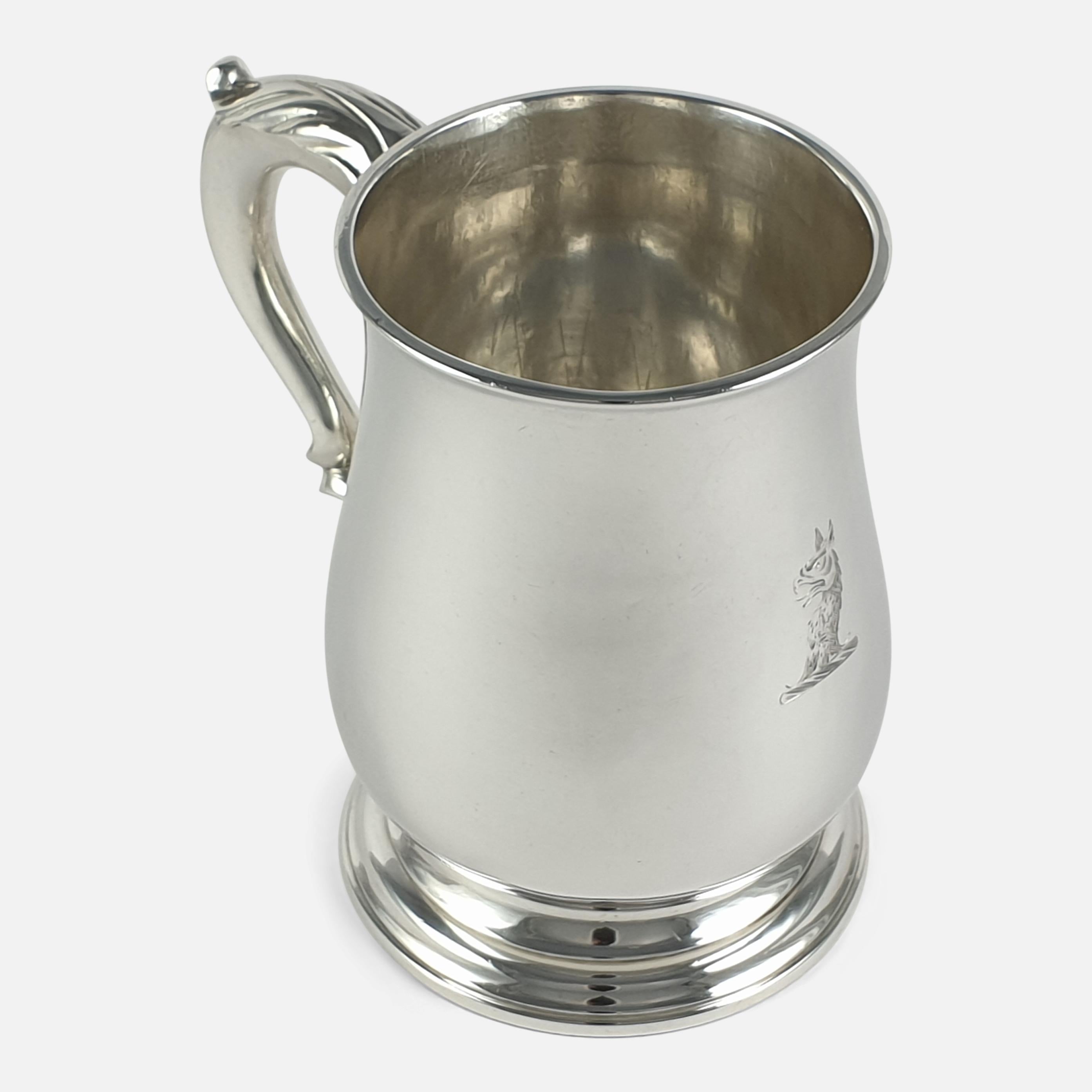 An early George III sterling silver mug by John Robinson II, London, 1766. The mug is of baluster form with a spreading foot and a leaf-capped scroll handle, and engraved with a family crest. It is hallmarked with the makers mark JR (John Robinson