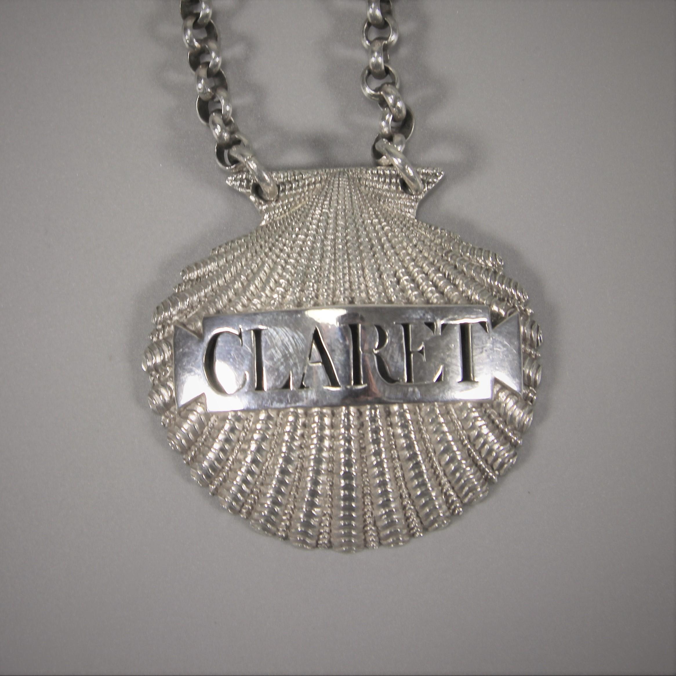 Pristine and beautifully made George III sterling silver shell claret label.
Made by Benjamin Smith II. London, 1807. 

The shell is cut in such a way that it sparkles as a background to the plain bar on which on which the word 'CLARET' is cut