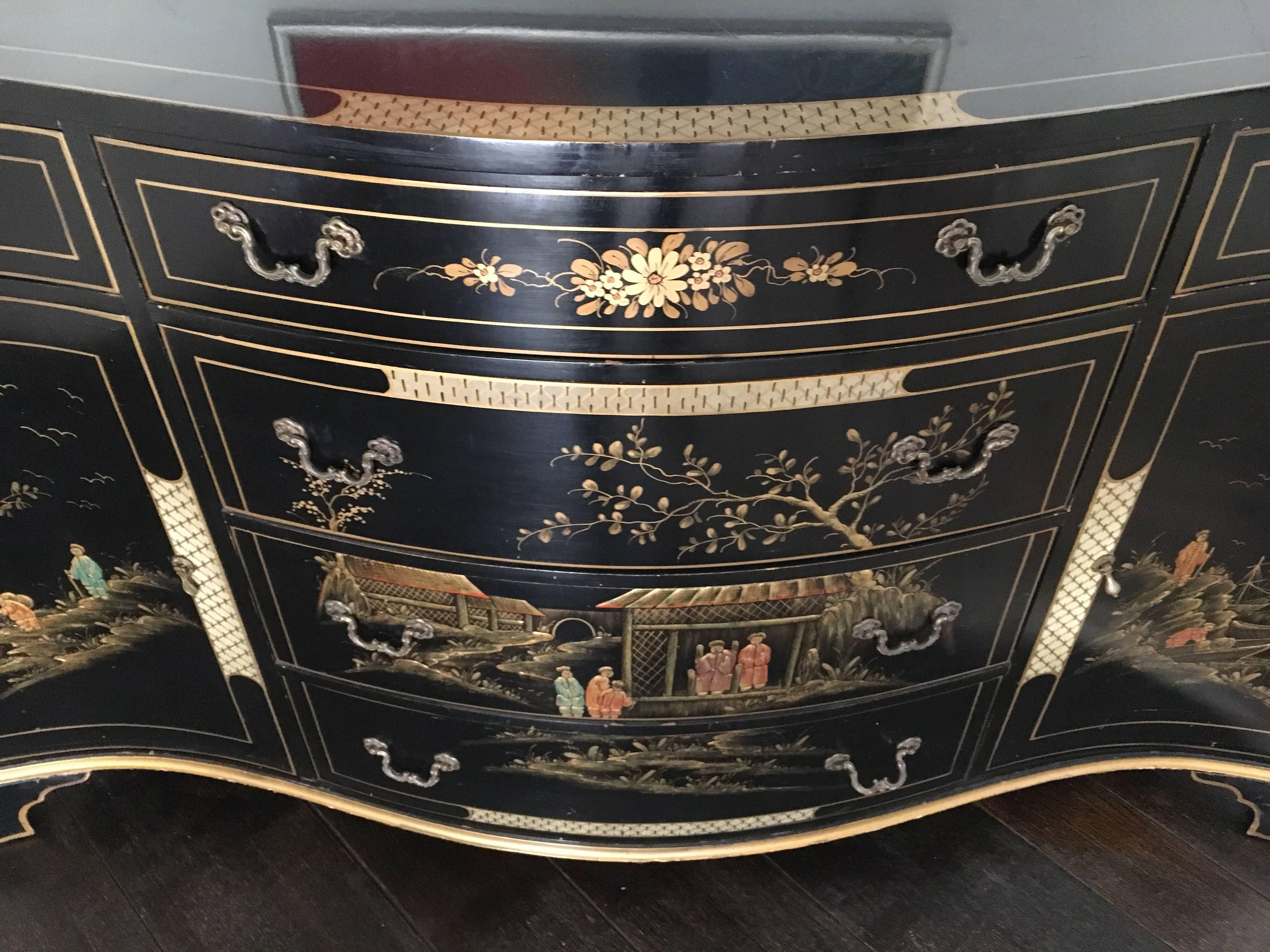 Exquisite black laquered chinoiserie server/buffet with gilt painted designs on front and sides. Has six drawers and two front doors that open to shelving. 