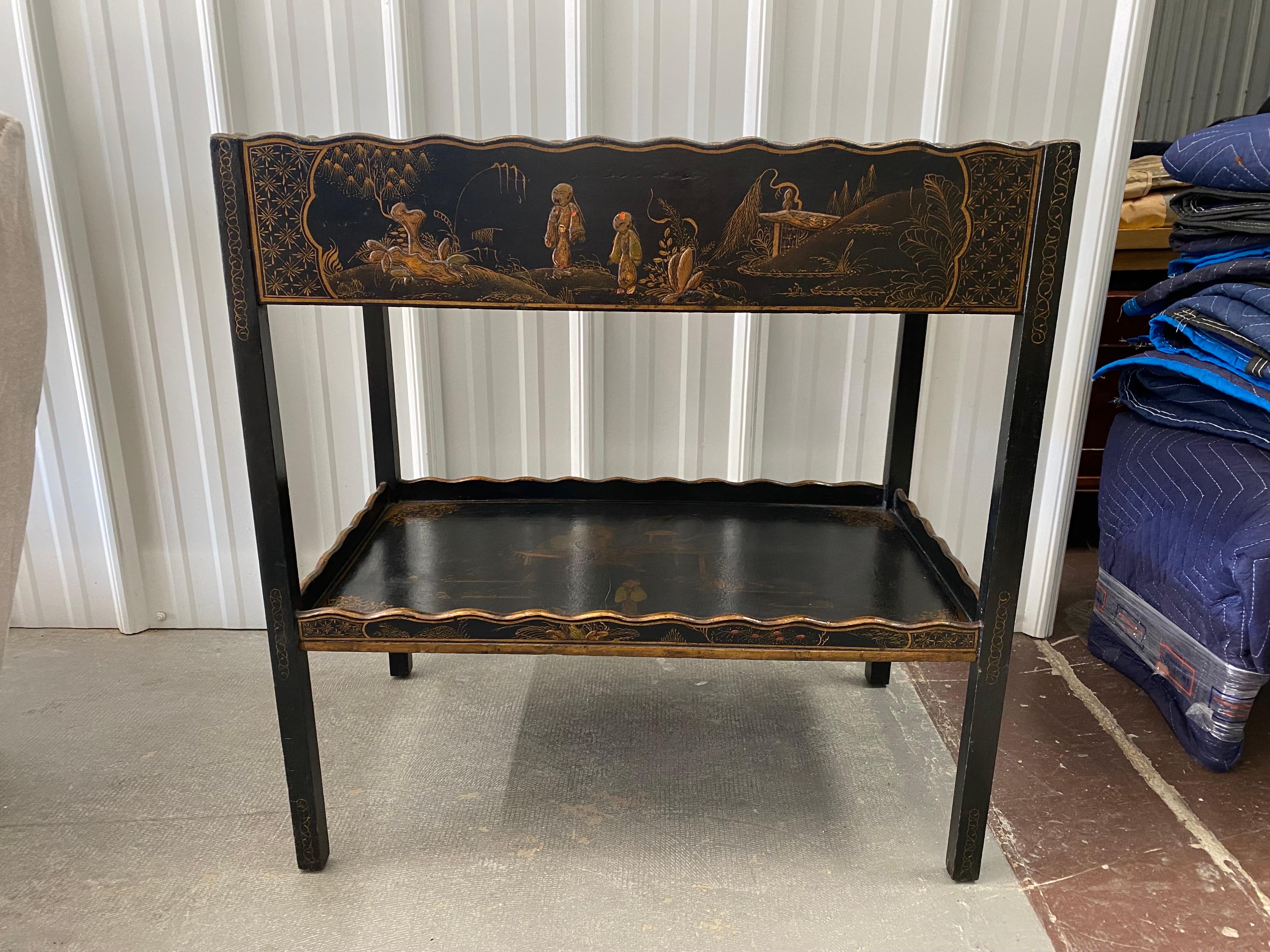 George III Style Lacquer Tea Table with Drawer.
A lovely narrow tea table, black lacquered, japanned with a beautiful elaborately painted scene on the top. Scallop edge rail on top and bottom shelf. Straight legs. A single middle drawer.
Small chips
