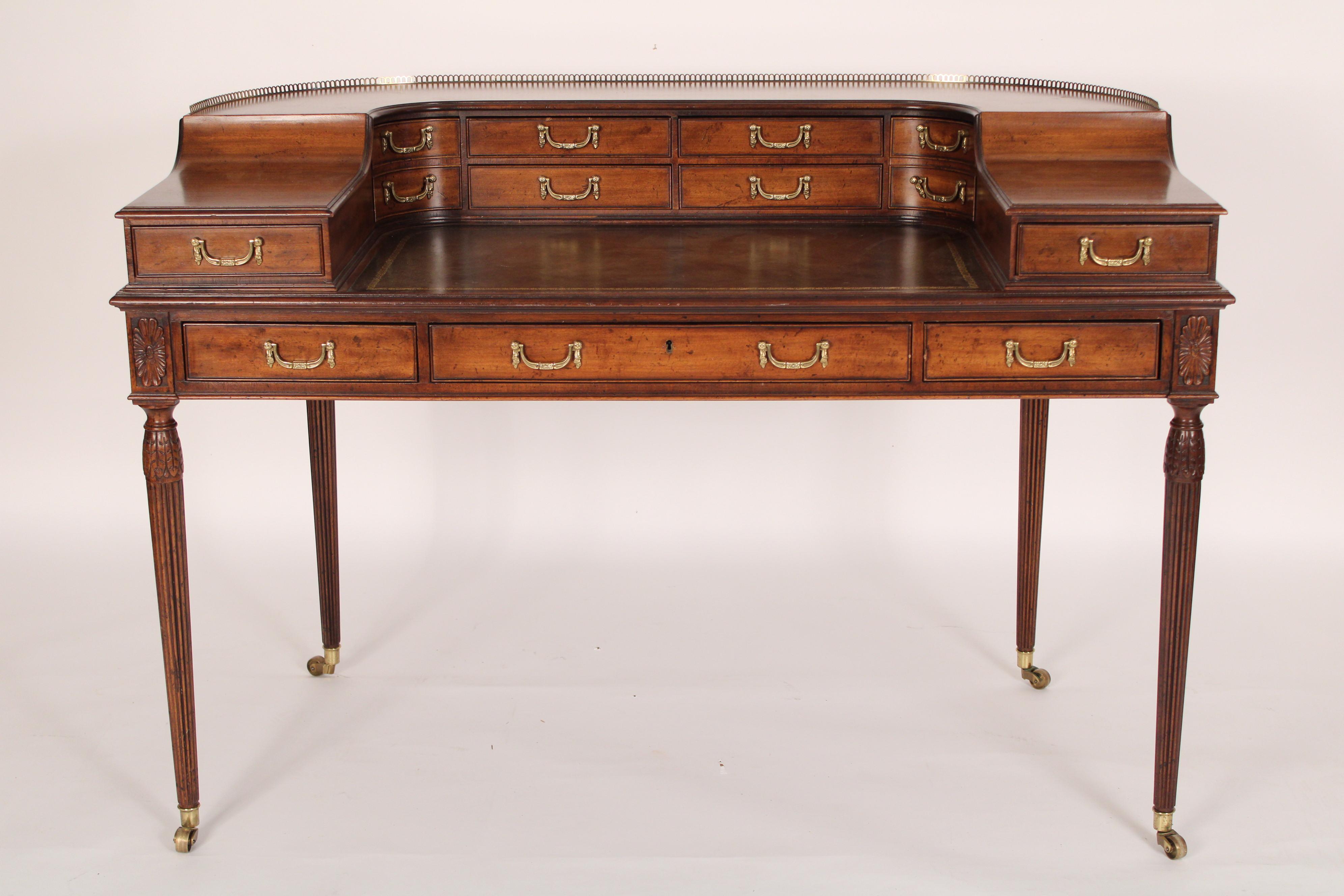 George III style mahogany Carlton House desk, made by Baker, late 20th century. The upper section with a pierced brass gallery and 8 drawers, a gilt decorated leather top, 3 frieze drawers resting on turned tapered reeded legs ending in brass