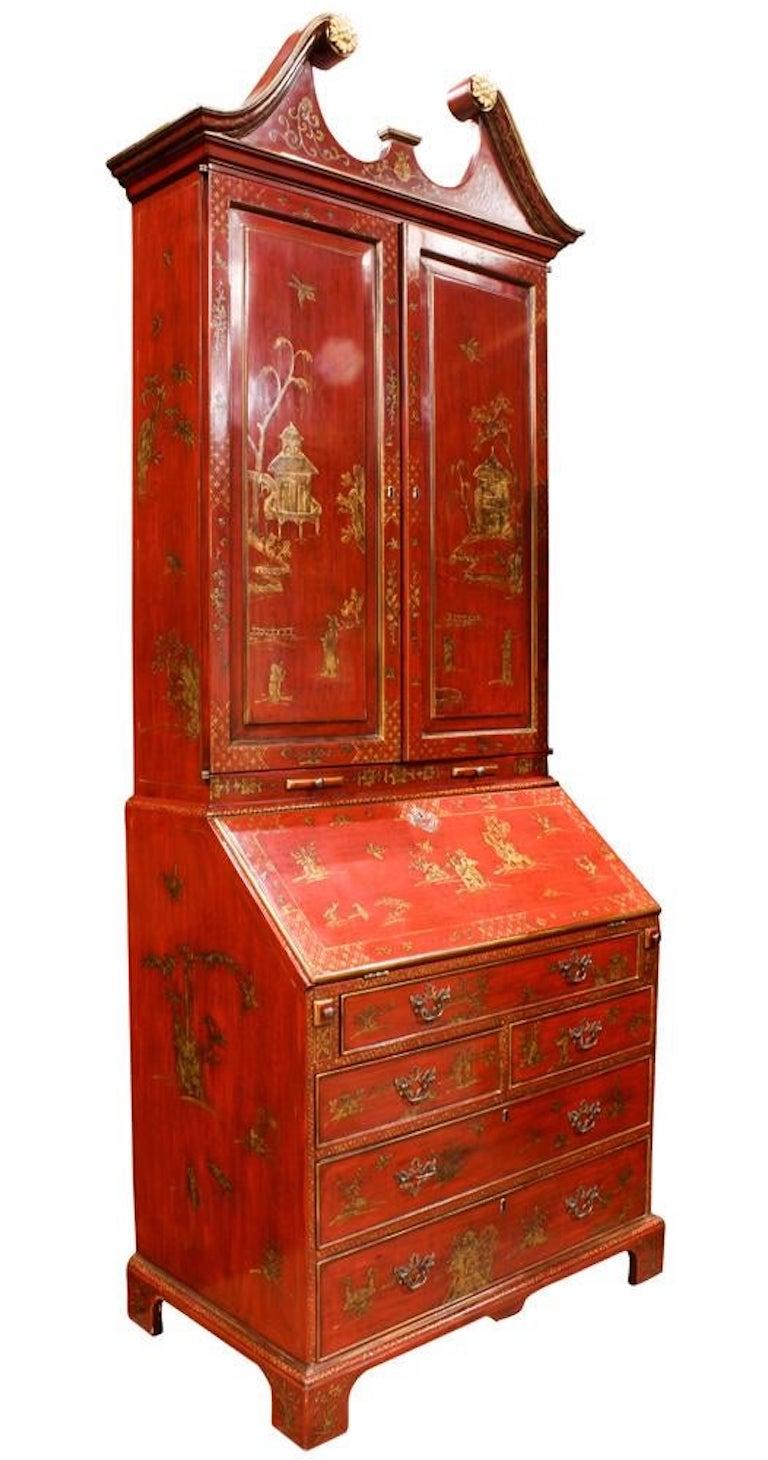 A George III style chinoiserie red lacquered bureau bookcase, the broken dentil cornice with gilt rosettes, over panel doors decorated with a pavilion and figures, opening to reveal three movable shelves, over a slant top opening to reveal an