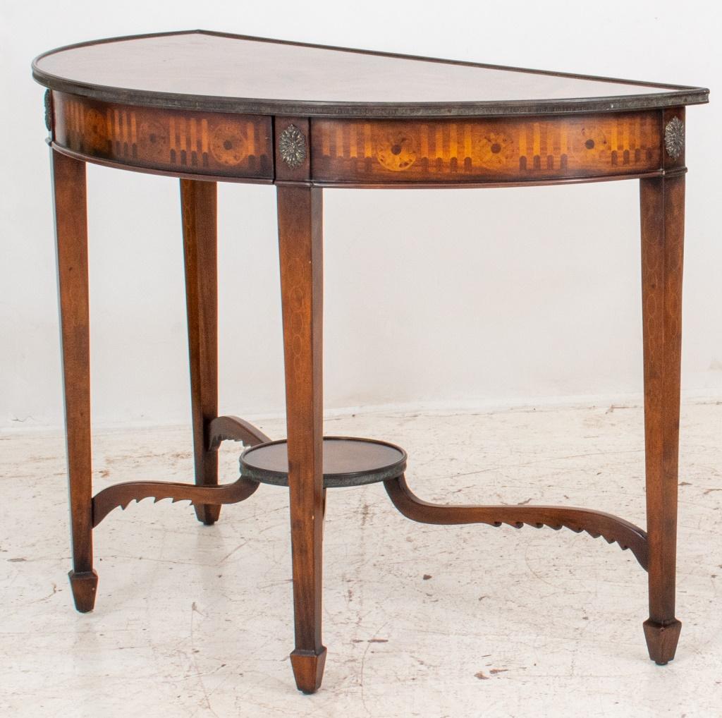 Theodore Alexander George III Style Demilune Table with bookmatched mahogany veneered top, and intarsia-decorated apron concealing a central drawer (interior with label of maker, Theodore Alexander) above tapering square legs conjoined by shaped