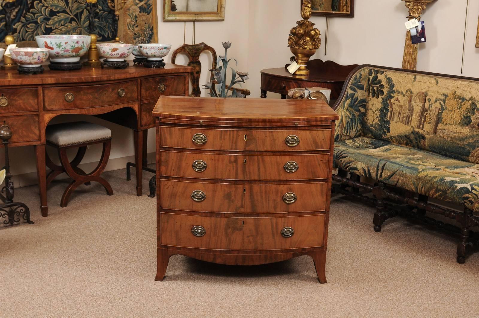 The bow front chest with boxwood string inlay on top, brushing slide and four graduating drawers with brass pulls over spayed feet. The mahogany with a nice faded patina.