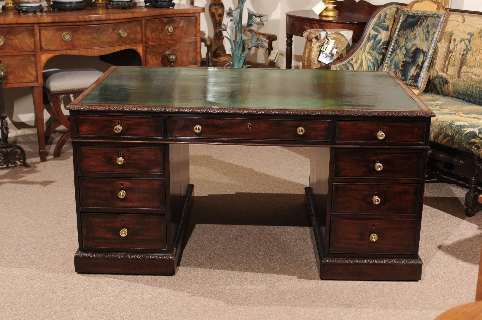 The rectangular top with carved boarder and embossed emerald green leather with nice patina. The frieze having one long drawer and two short drawers above three graduated drawers. The reverse side with one long drawer and two short drawers above