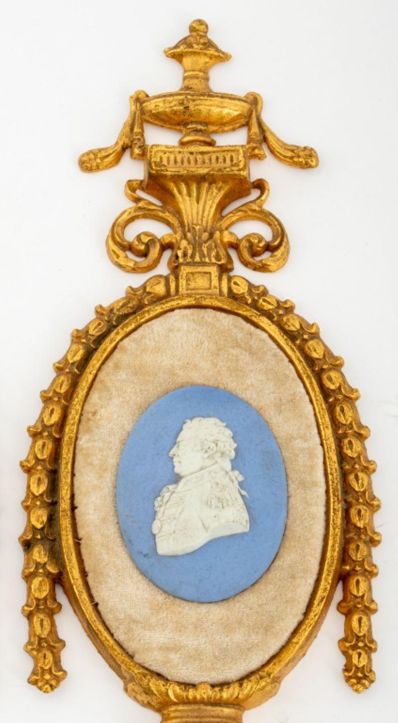 George III style gilt bronze appliques, 2, in the manner of the Brothers Adam (Scottish, XVIII-XIX) in the form of garlanded urns above scrolls and garlands centering an oval frame containing Wedgwood Blue dip portrait medallions on velvet, with