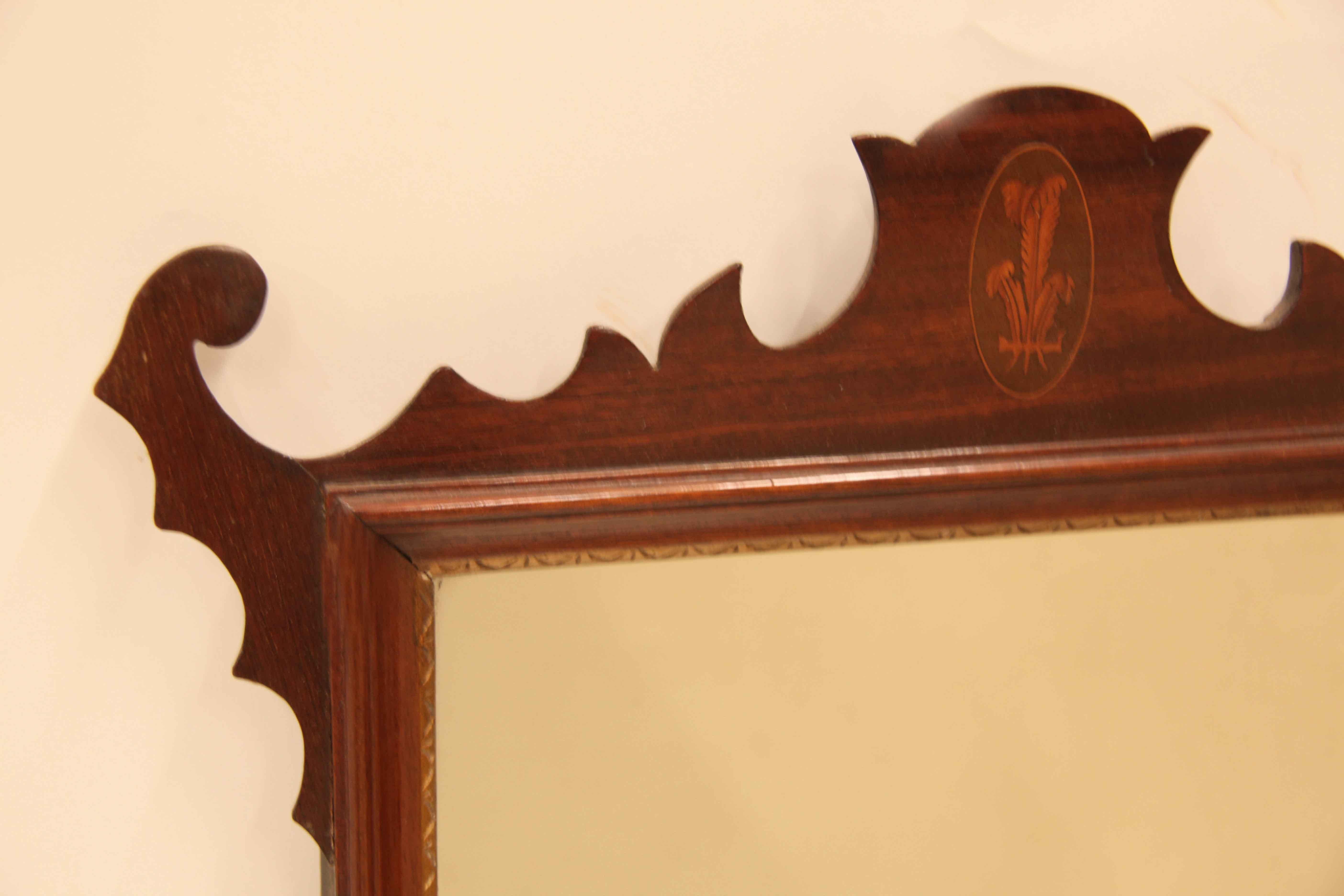 George III style inlaid mirror, the top has a beautiful design( repeats at the bottom) with a Prince of Wales plume inlaid in the center. The original glass mirror is framed by a hand etched demi lune motif in gold inside a concave molding.  This