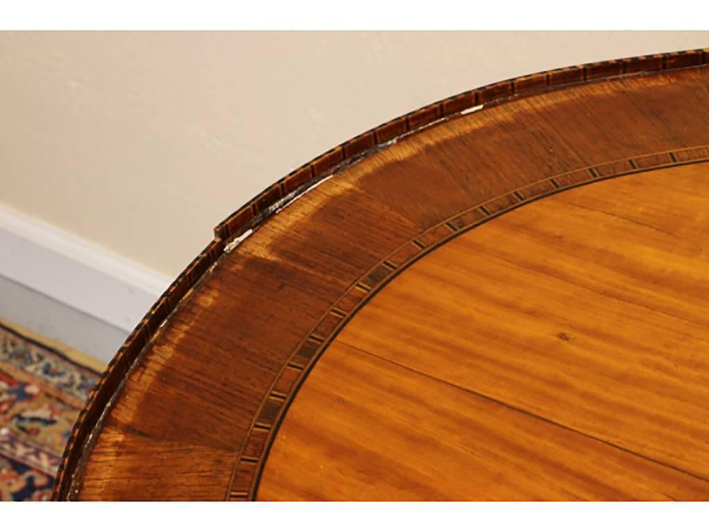 Satinwood and rosewood banded top with centre fan medallion an overhanging top with inlaid edge and shallow gallery. The apron with two patterned inlaid bands and raised on square tapering banded legs.

Dimensions: 40” wide by 28.75” deep by 29.5”