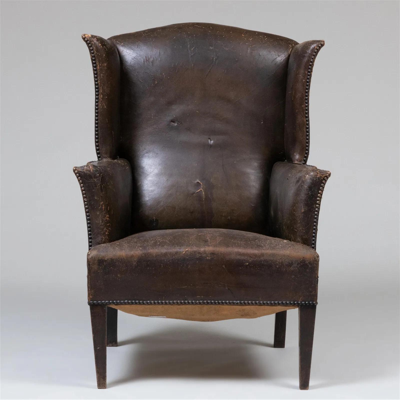 George III style leather wingback chair.  The chair has its original leather and is worn in some areas with solid wood legs.  