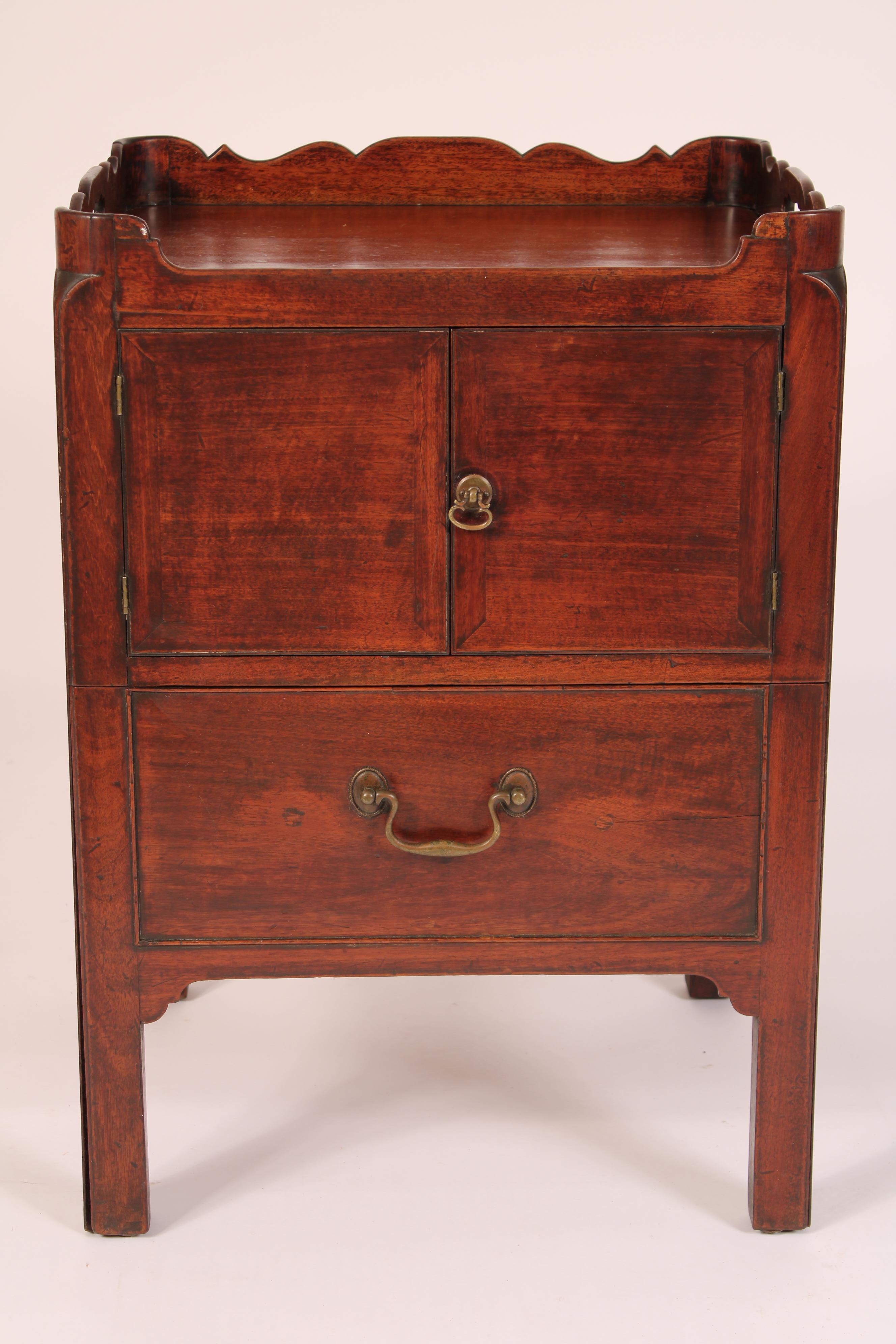 George III mahogany bedside table, circa 1780. The mahogany top with back and side scalloped gallery with carrying handles, below are two doors, below the doors is a pull out drawer, resting on square Georgian legs. Nice old patina. This bedside