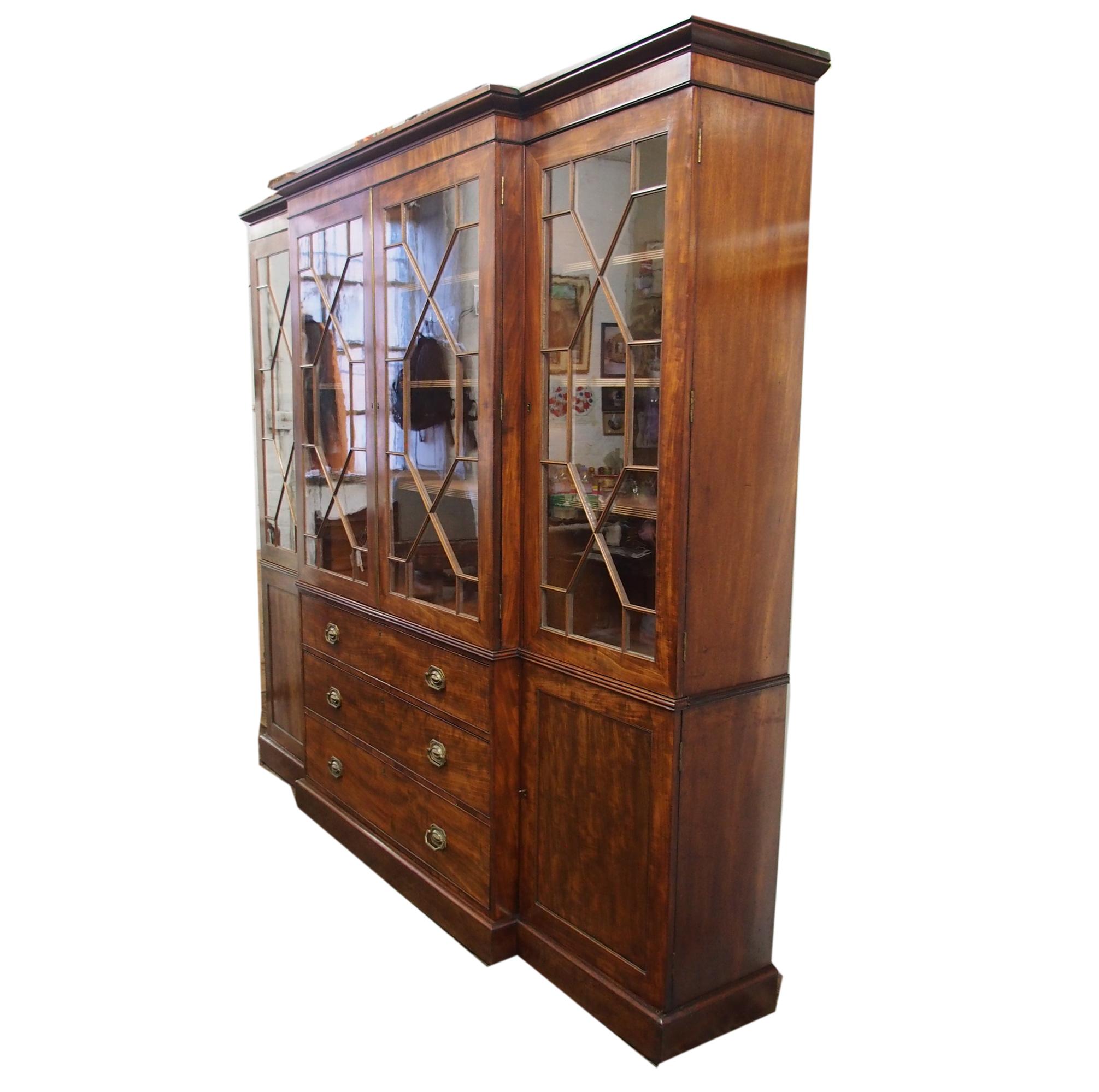 With restorations, George III style breakfront bookcase in figured Spanish mahogany with a mellow color, circa 1850. Surmounted by a moulded cornice and crossbanded frieze, the 4 astragal glazed doors open to shelved interiors. The base with 3 long