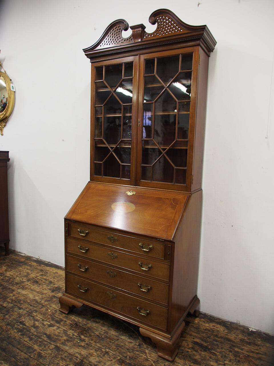 George III style mahogany bureau bookcase, circa 1880. The tall arched swan neck pediment with open fretwork sits over a moulded dentil cornice. The twin astragal glazed doors open to reveal three adjustable shelves, and the bureau has a shell and
