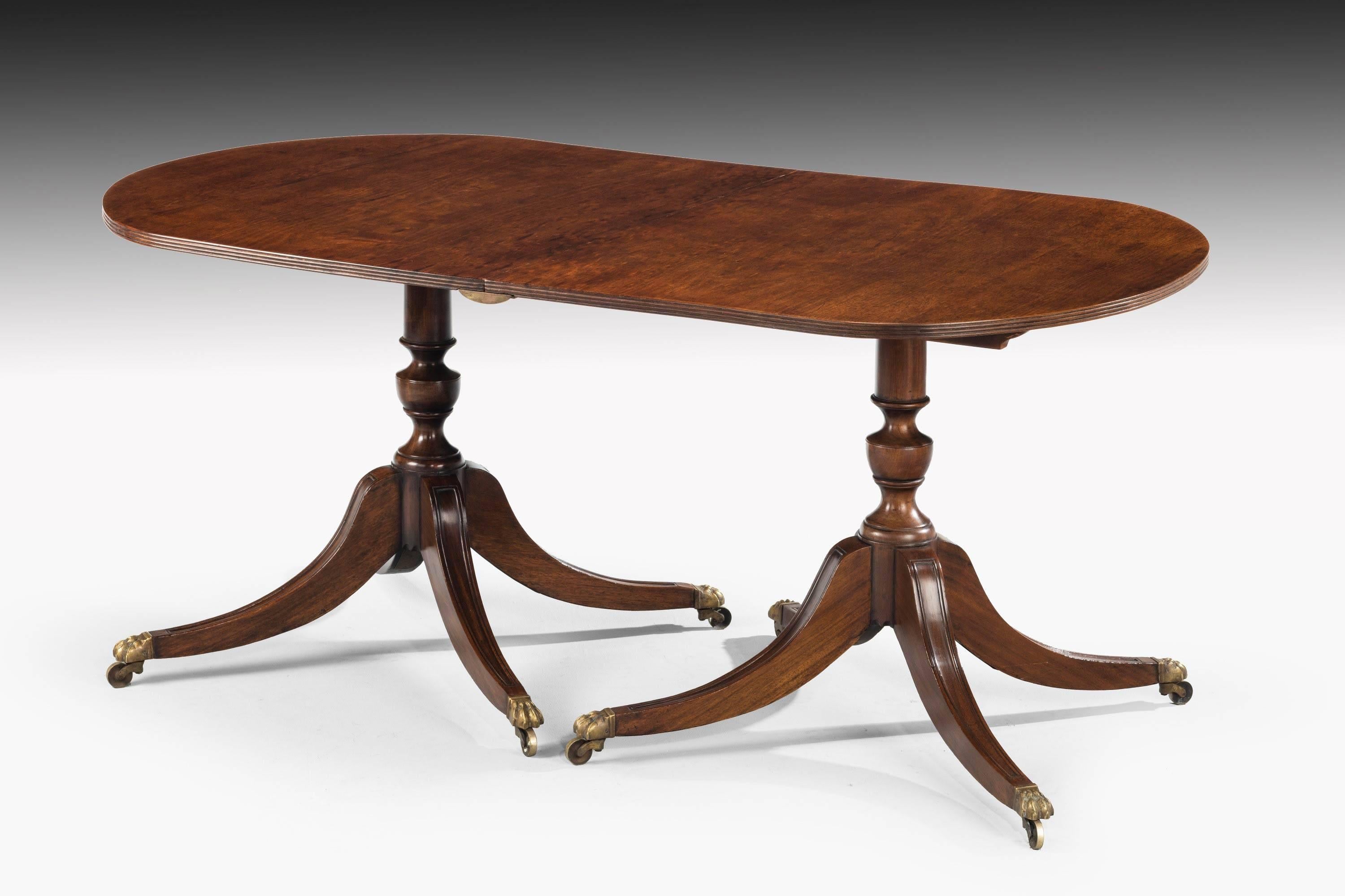 A George III style mahogany dining room table with a pair of shaped centre corns, Swept quadruple base with one extra leaf.
