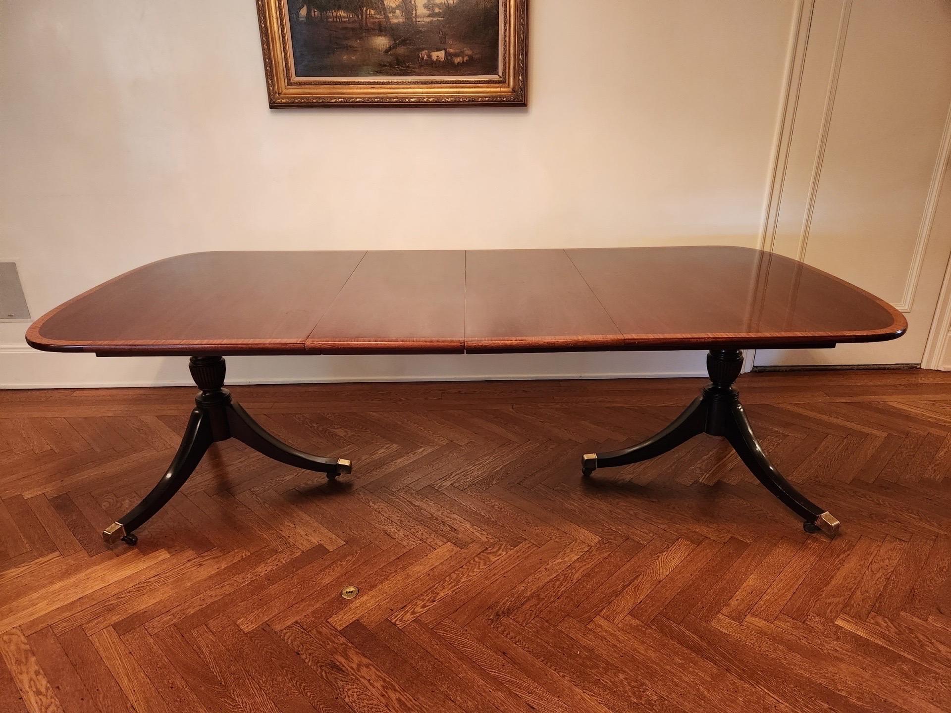 George III Style Mahogany Double Pedestal Dining Table with Inlaid Cross Banding, 20th Century
A very nice and well proportioned George III style reproduction dining table with double splayed pedestal bases ending with brass feet on casters. A