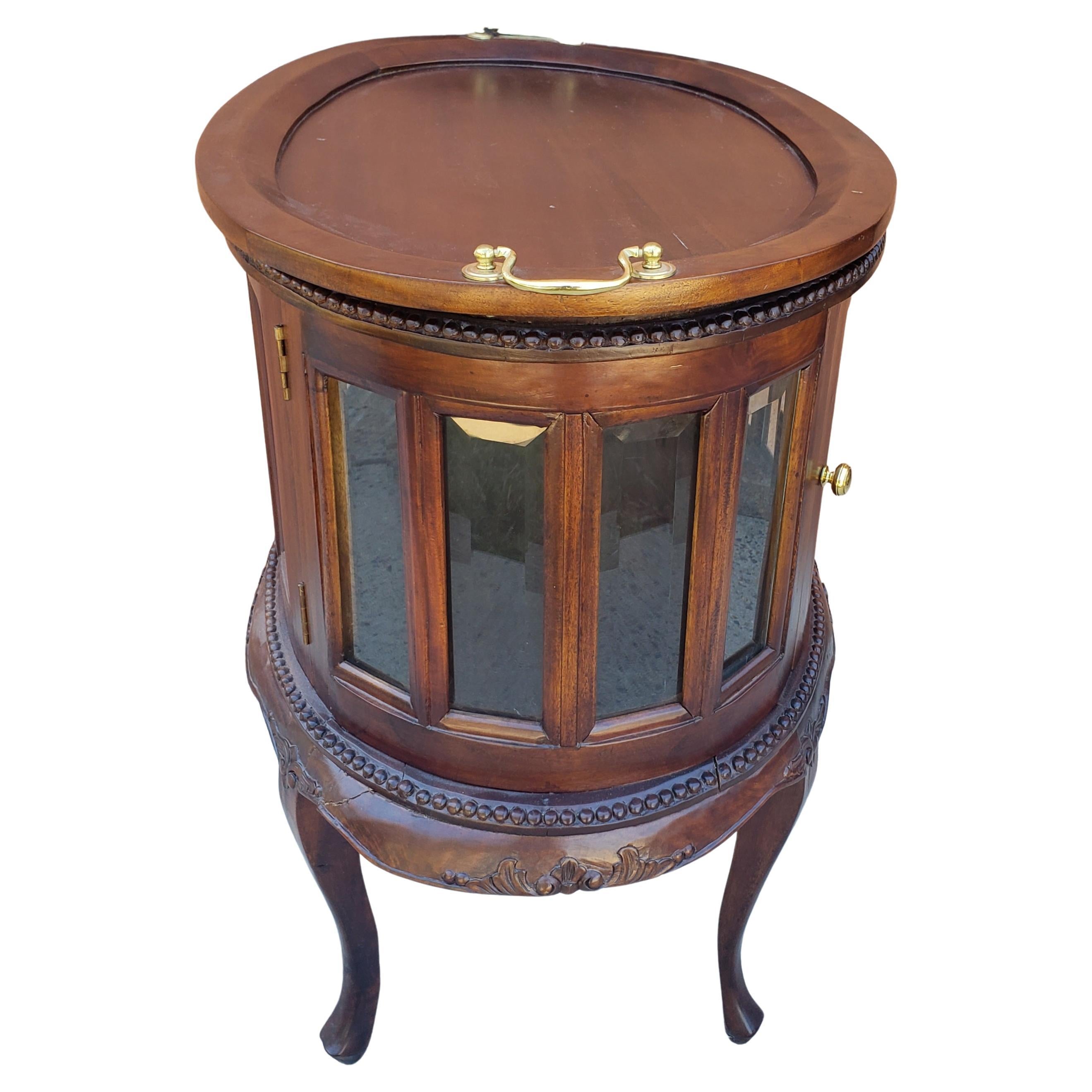 An exquisite George III style Mahogany oval vitrine table with removable two-handle tray top. Features two doors in front and rear and identically finished on both both side, making usable as a center table. Use to store your wine and liquor