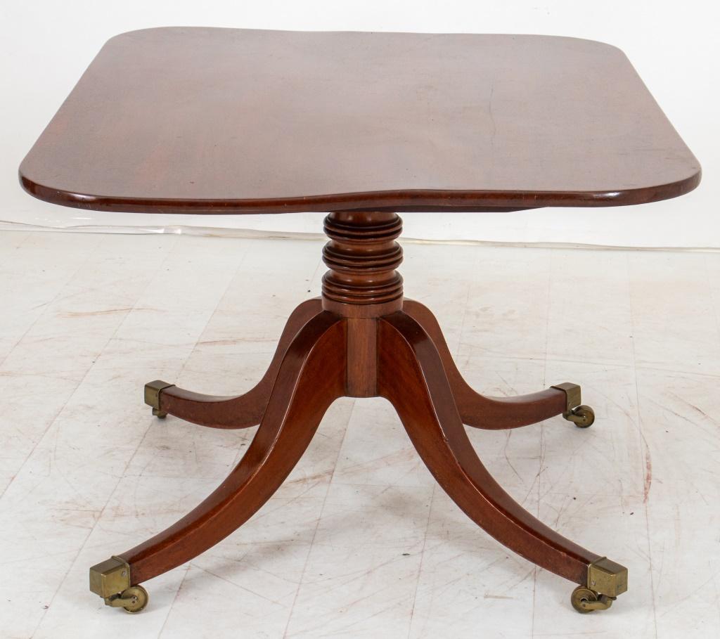 George III mahogany wood tilt-top pedestal table, circa 19th century, with rounded rectangular top above a central pedestal with four splay legs on caster wheels.  28.5