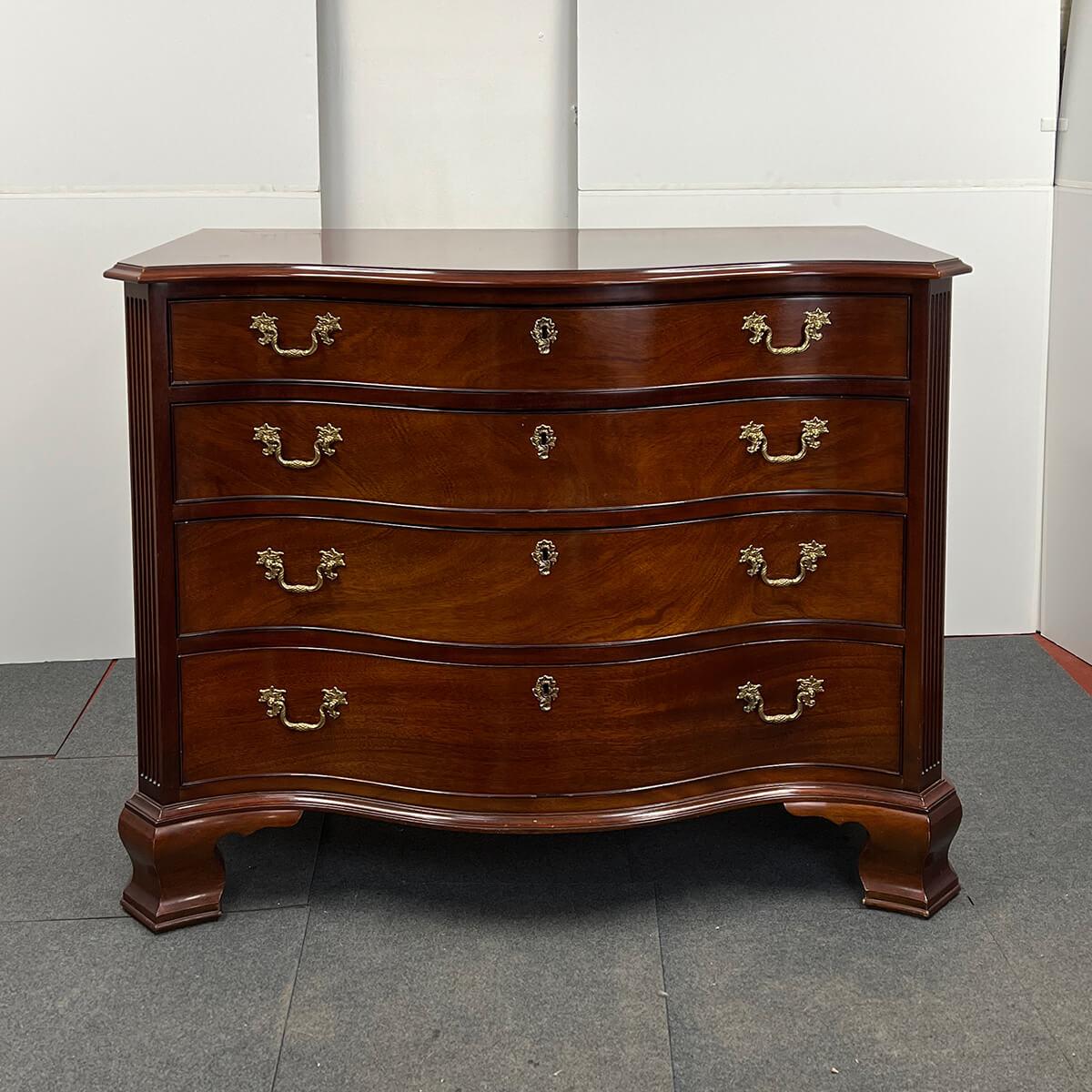 George III Style mahogany serpentine chest of drawers, with a shaped and molded edge top, above four graduated drawers, the top one being fitted with sections, with canted and fluted corners on shaped ogee bracket feet. Late 20th century, by Kindel
