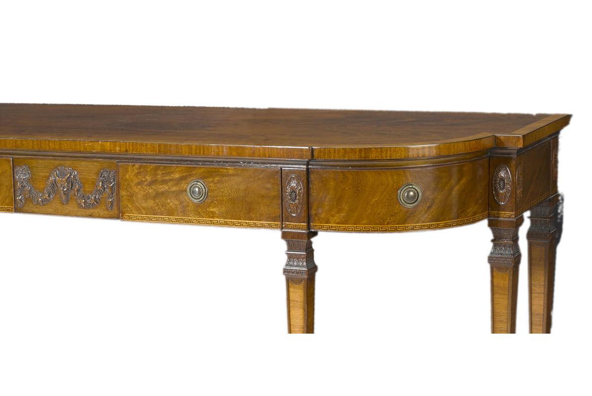 Imposing and large 19th century English George III style mahogany six-legged sideboard.
The D-form top over frieze fitted with two front drawers and two corner drawers decorated with carved medallions, centred by a carved mask with swagged garlands