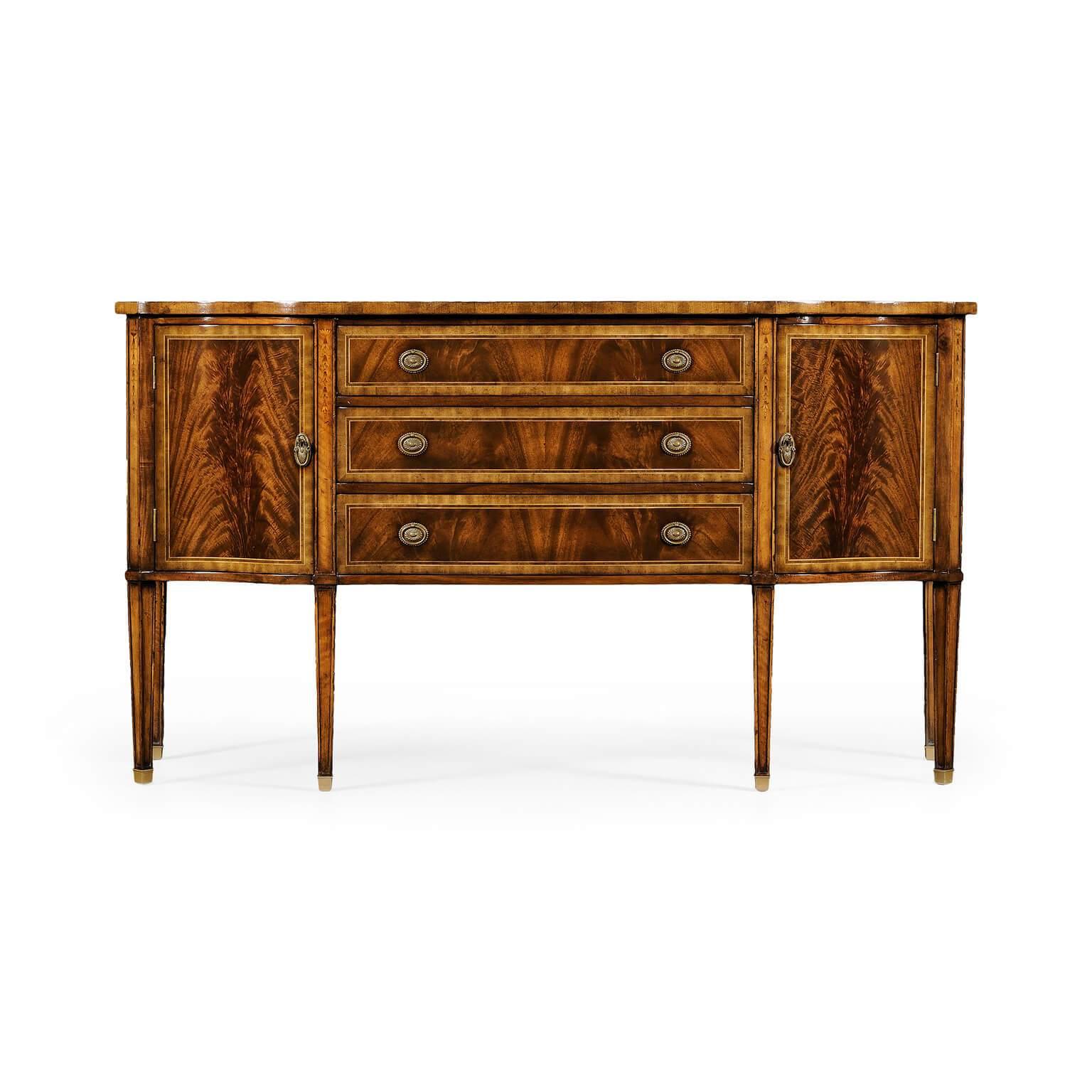 George III style crotch mahogany veneered serpentine sideboard. The breakfront with concave doors to either end and with three drawers to the center. Patinated brass oval handles, fine marquetry detail to the paneled tapered legs and set on brass