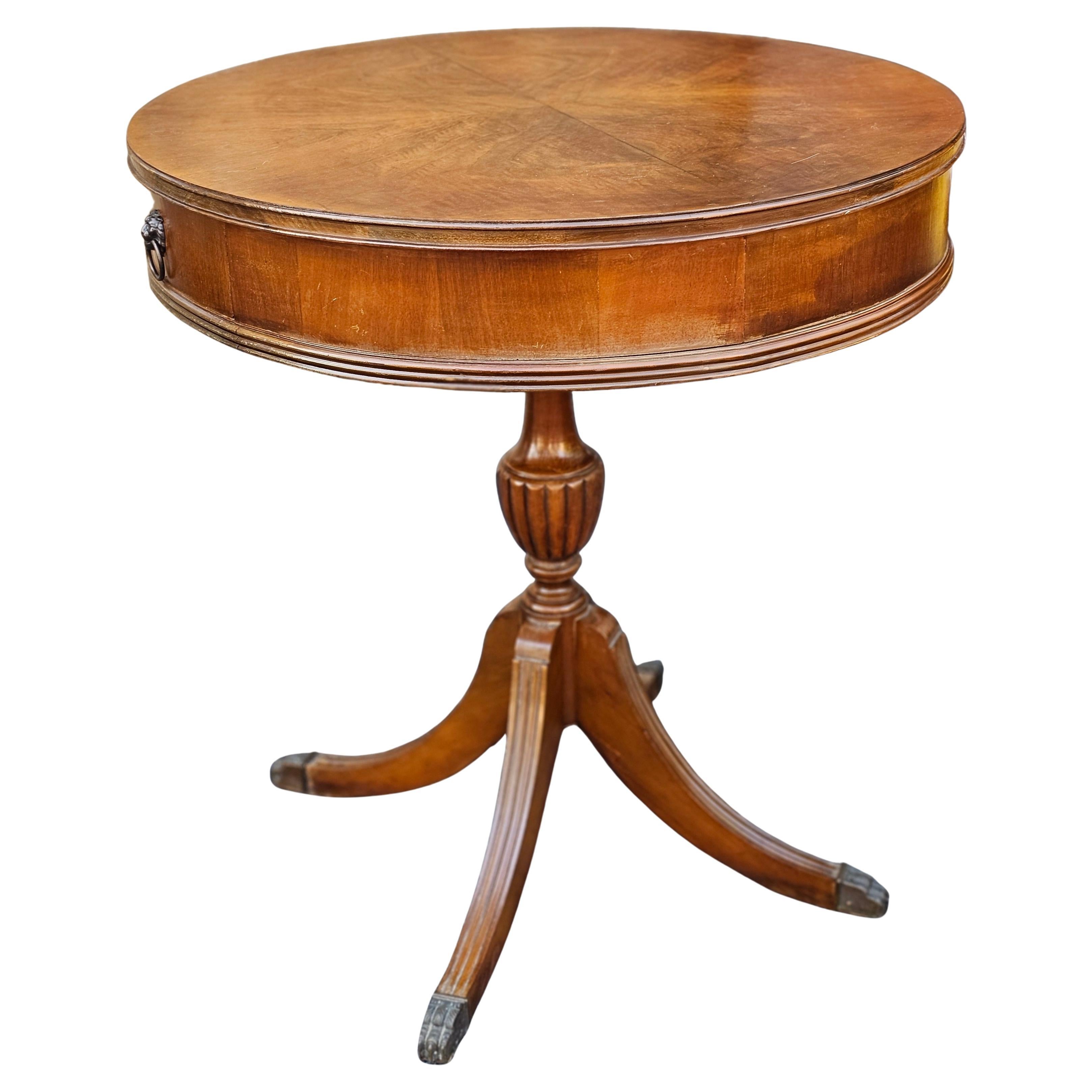 A George III Style Mahogany Two-Drawer Drum Table on quad-leg pedestal terminating with brass cap paw feet.
Measures 26