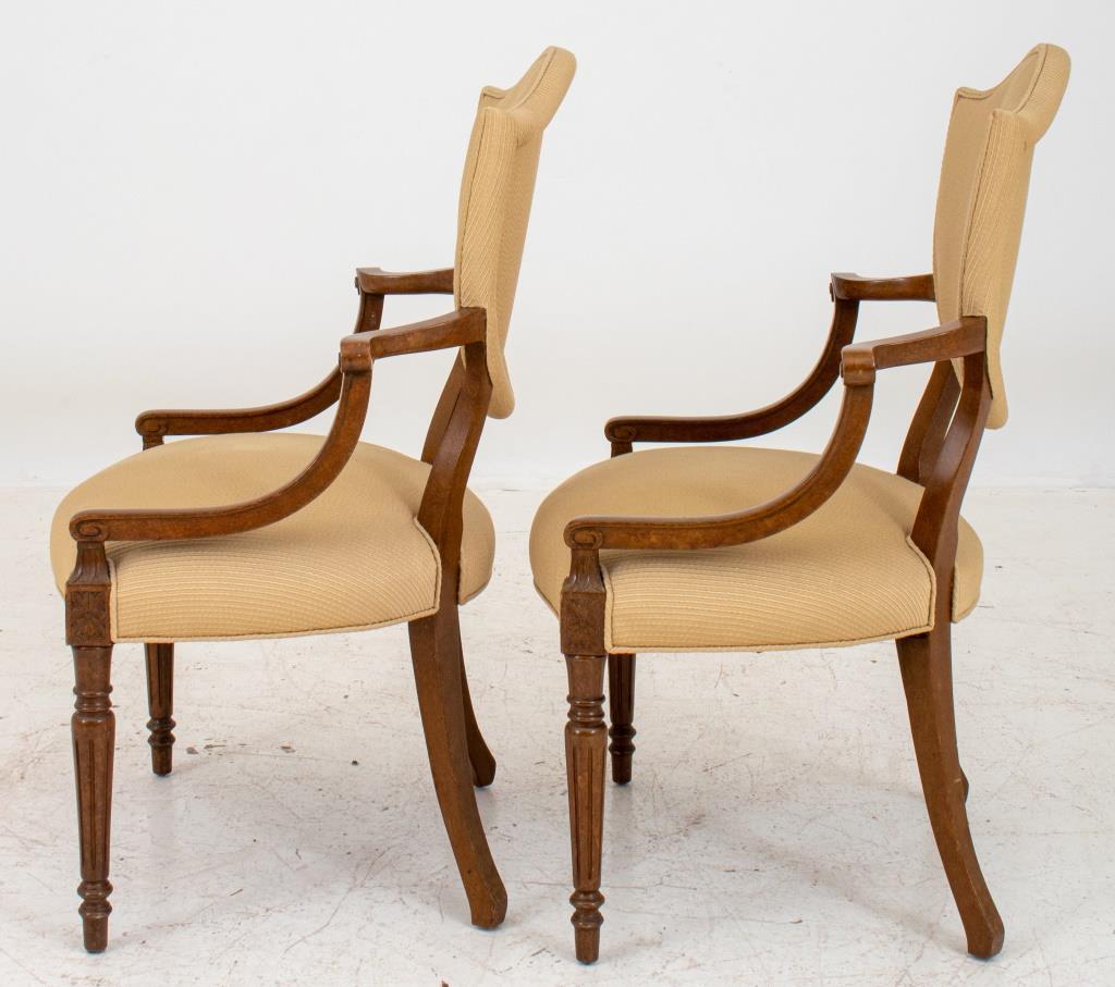George III style shield back arm chairs in the manner of Thomas Sheraton (English, (1751-1806), a pair, the shield-form backs issuing down swept arms above a shaped serpentine-front seat with paterae headed  tapering columnar fluted legs terminating