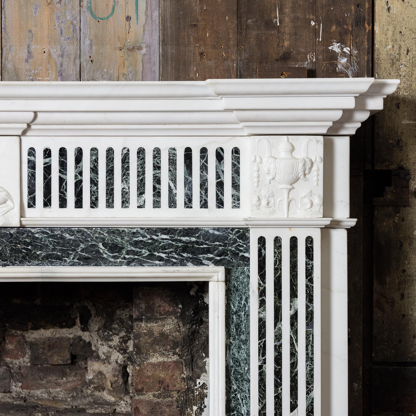 George III style Statuary and Verde Antico marble chimneypiece, early twentieth century, the inverse breakfront shelf above inlaid frieze centred by relief carved frieze of the Goddess Iris / Flora, the jambs with conforming marble inlay, all raised