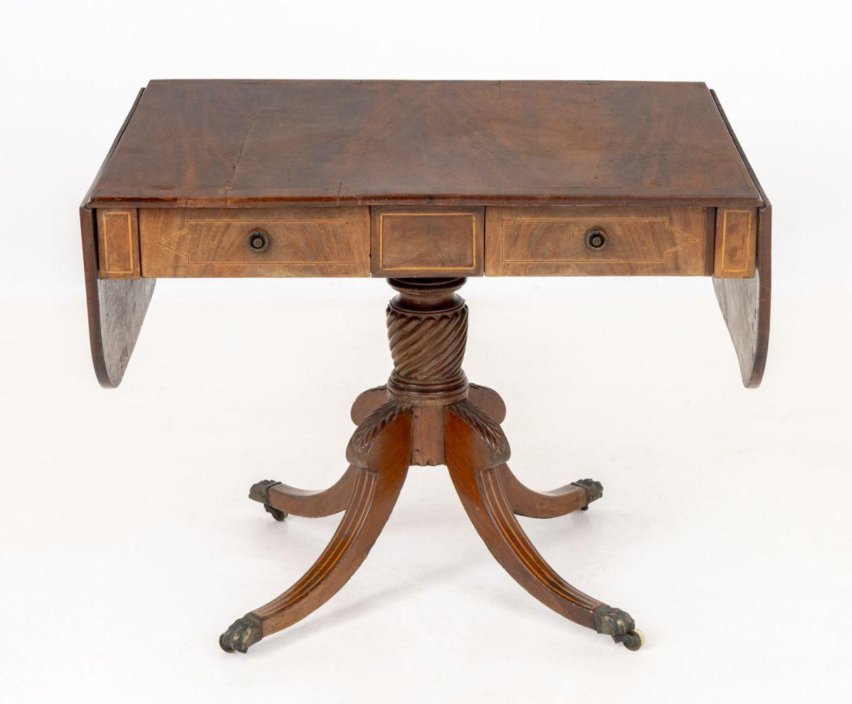 George III Style String Inlaid Mahogany Sofa Table, with two drop leaves and two drawers above four legs terminating in lion's paw feet above casters. Leaves dropped: 26.5