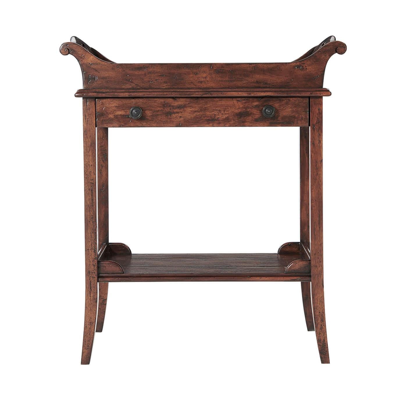 A George III style antiqued wood side table, the trough-shaped tray top with pierced handles above a frieze drawer, on splayed legs joined by a part galleried planked under tier. 

Dimensions: 28